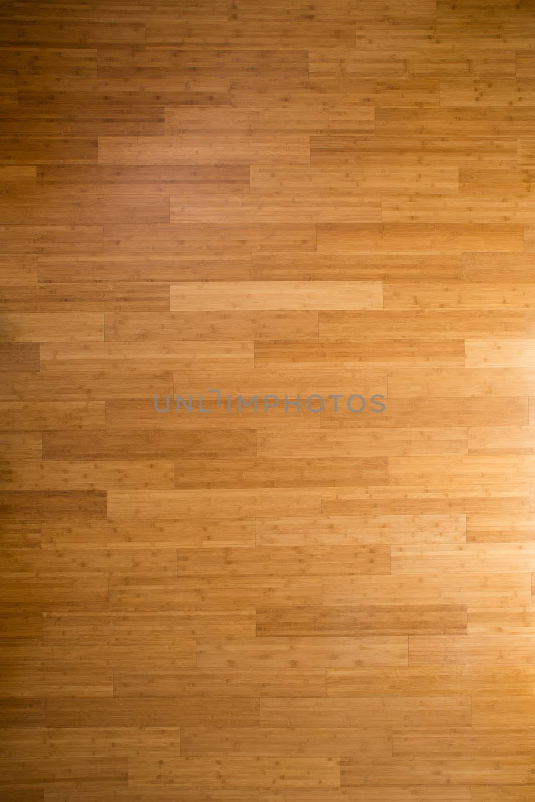 Background texture of a wooden bamboo floor with laminated floorboards, viewed overhead with side lighting and a gradient for an architectural or interior decor theme