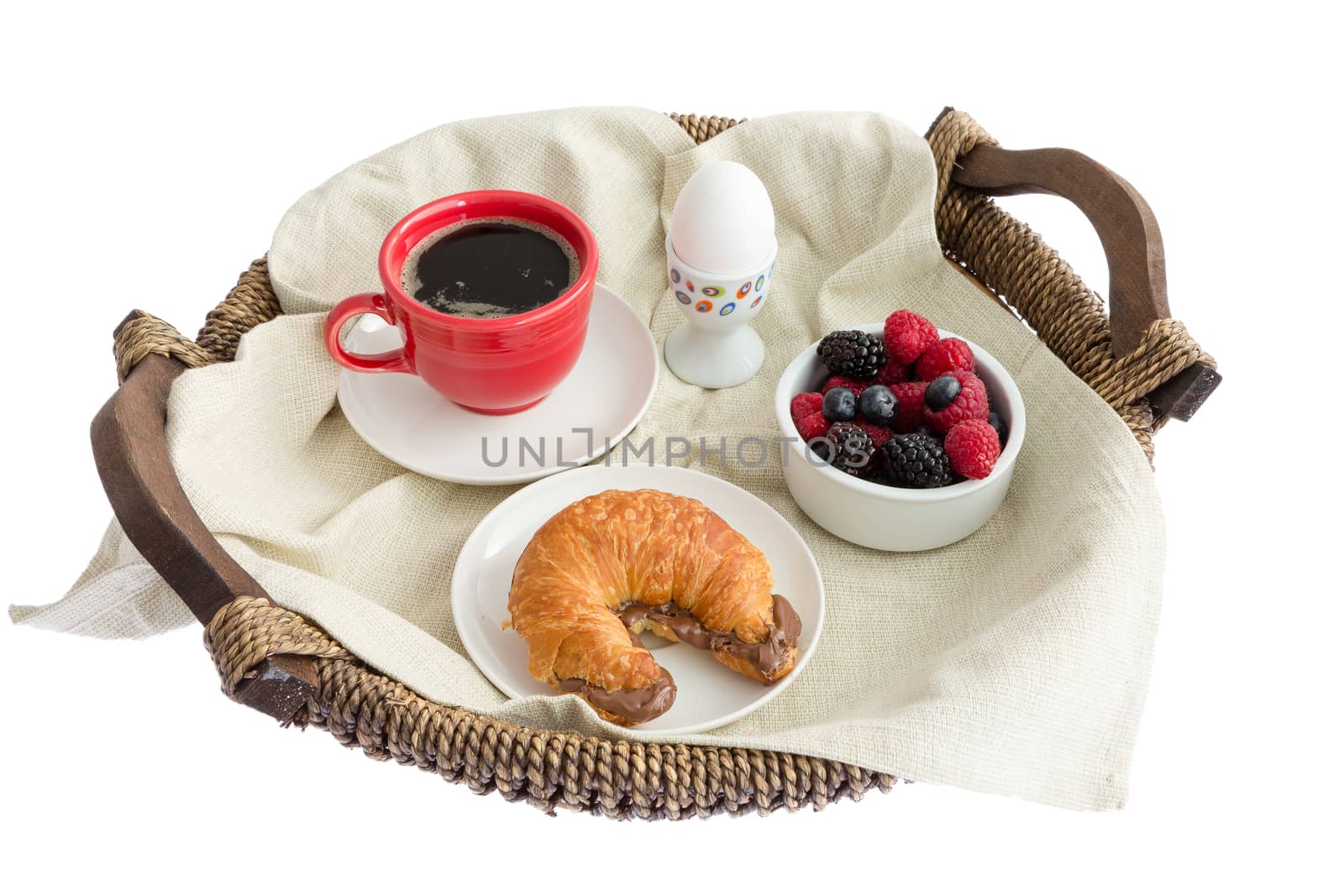 High Angle View of Appetizing Breakfast Tray - Hard Boiled Egg, Black Coffee, Bowl of Mixed Berries, and Croissant with Hazelnut Spread - on White Background
