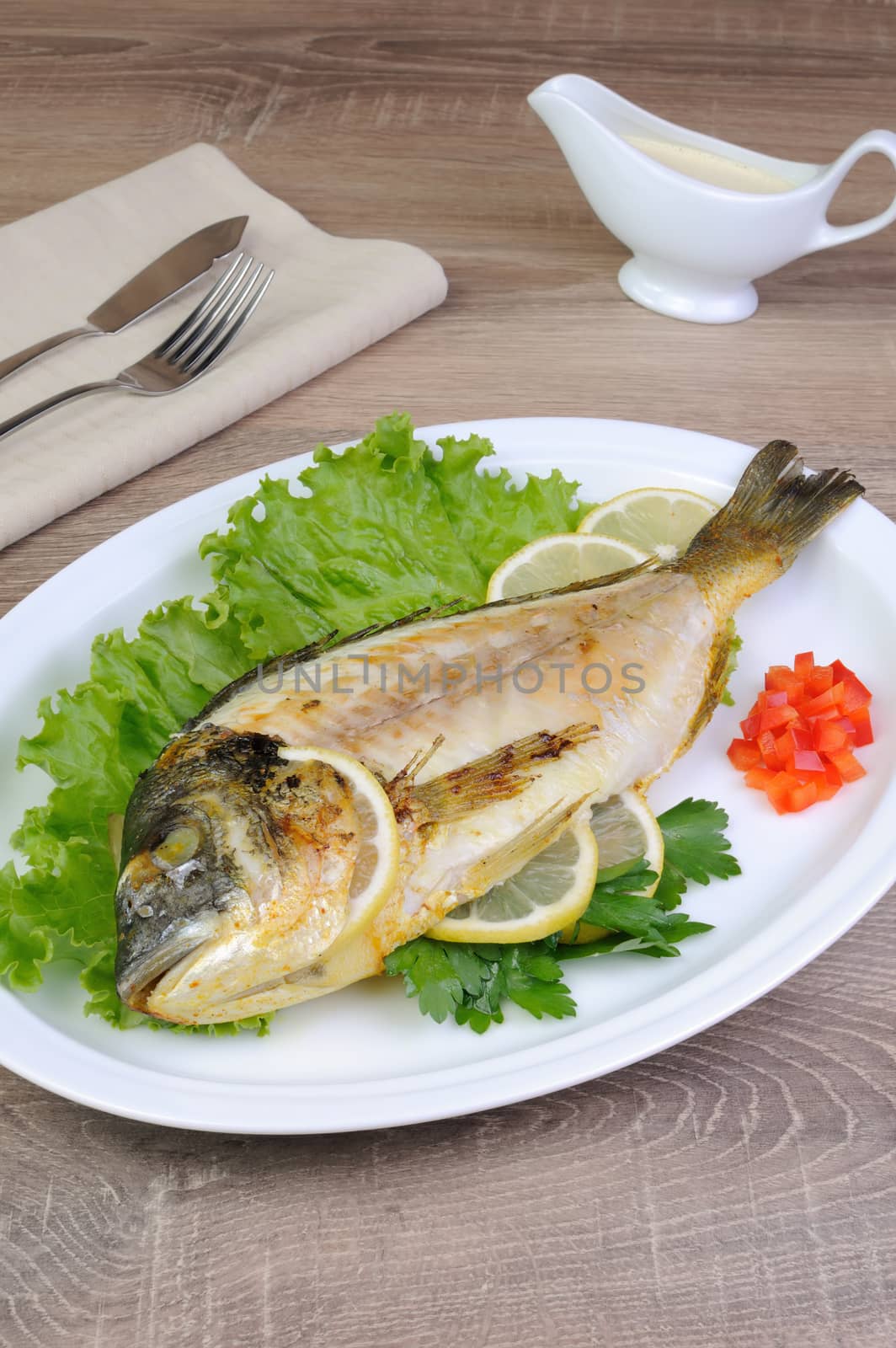 Baked fish Dorado in lettuce leaves with lemon