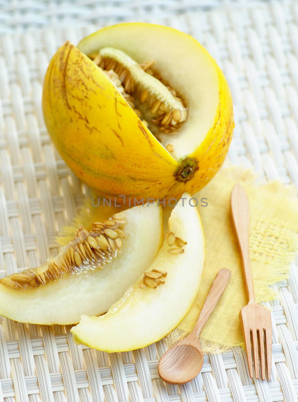 Fresh Ripe Melon Full Body, Slices with Wooden Fork and Spoon closeup on White Wicker background