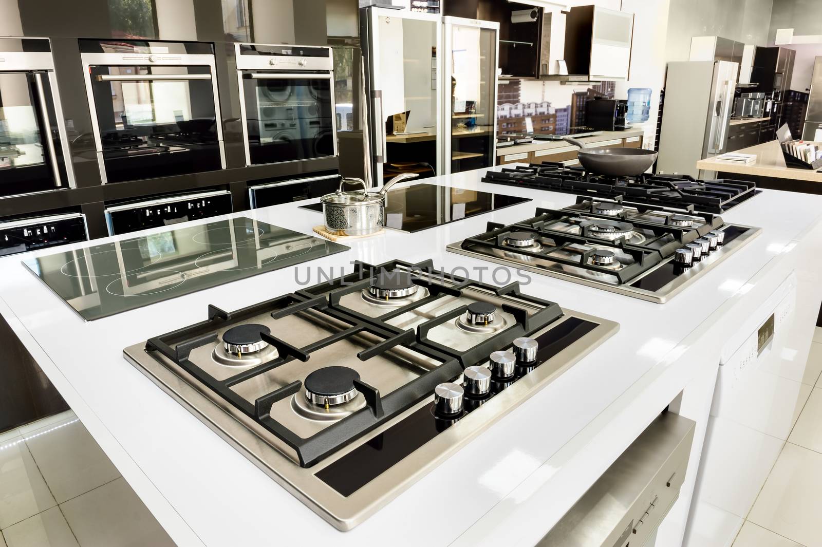 Rows of brand new gas stoves and ovens with stainless steel trays in appliance retail store