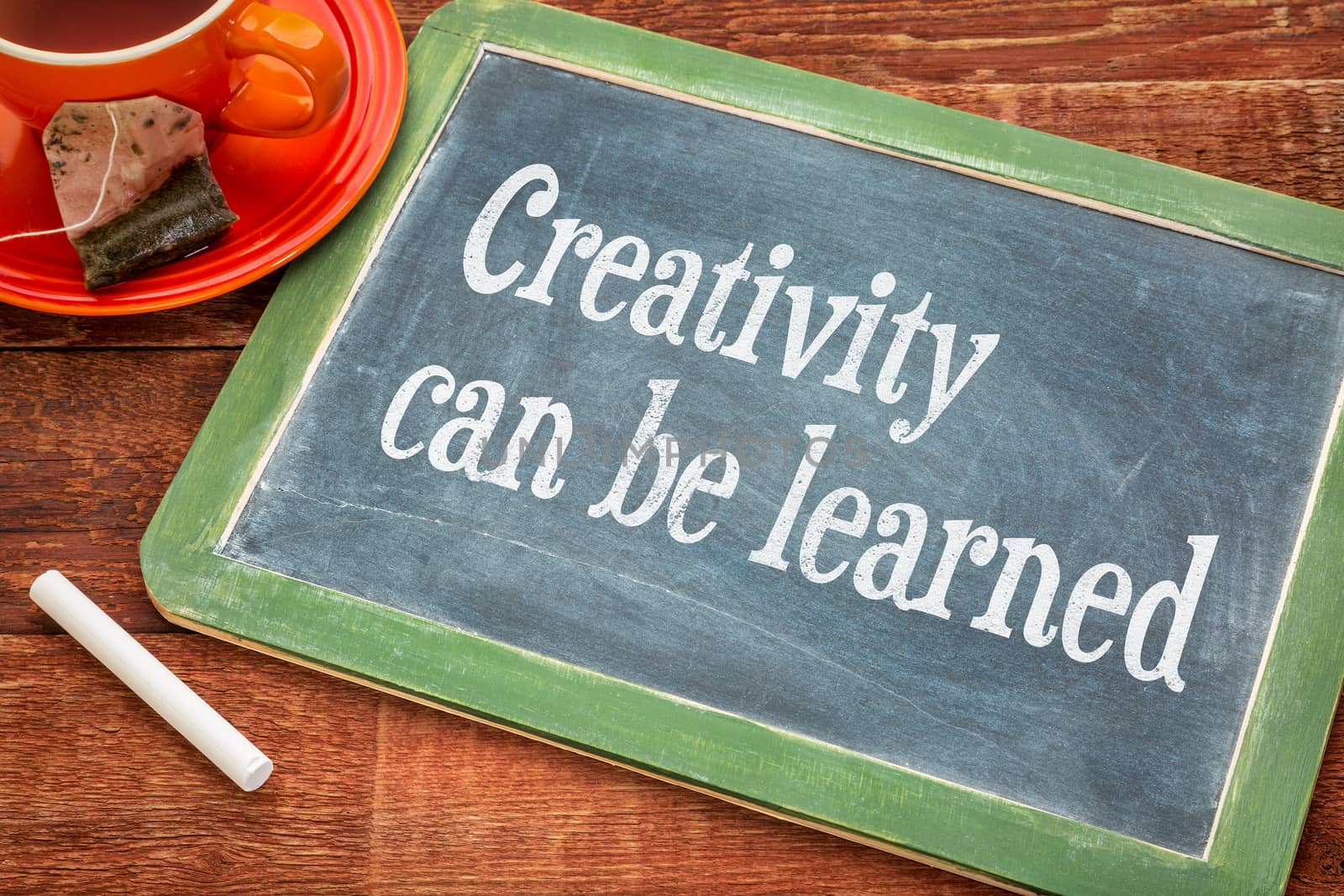 creativity can be learned- motivational text on a slate blackboard with chalk and cup of tea