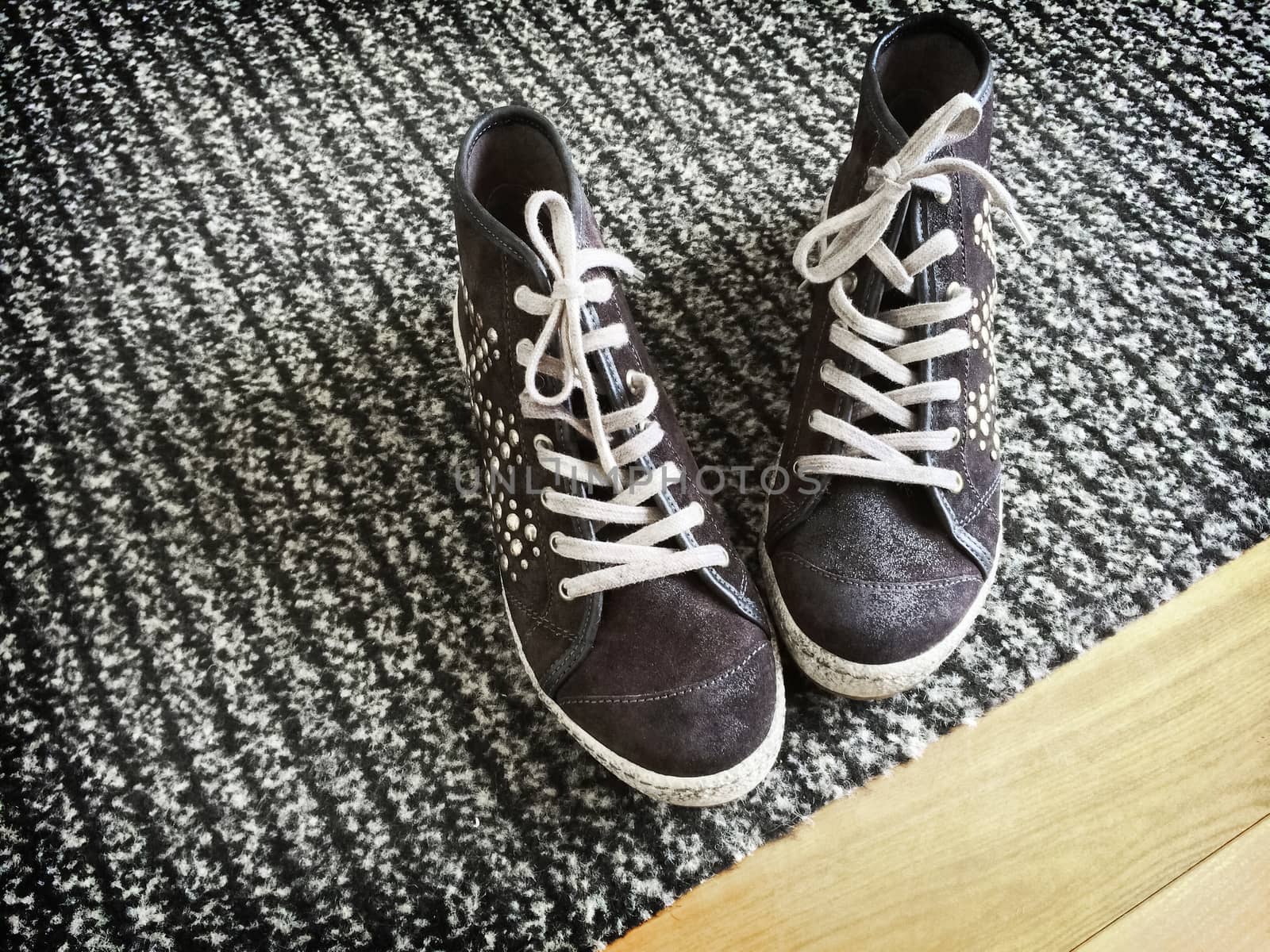 Fashionable shoes with metal rivets on gray striped carpet.
