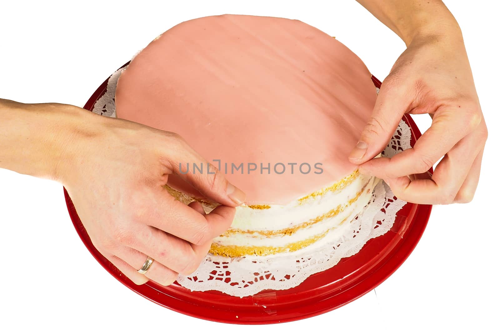 Professional cake baker making the final touch when covering a cream cake with pink marzipan