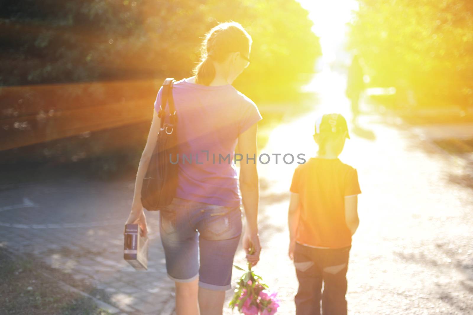 Blurred photo of walking woman with her son on sunrise
