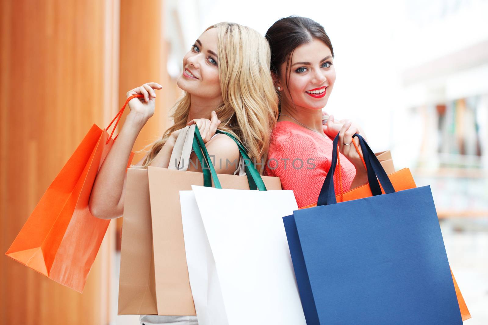 Young beautiful happy women with shopping bags in mall