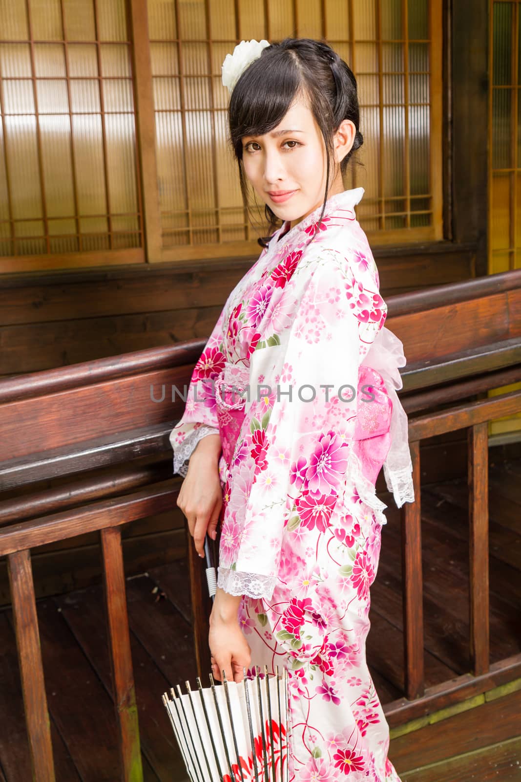Asian woman wearing a kimono in front of  Japanese house holding umbrella