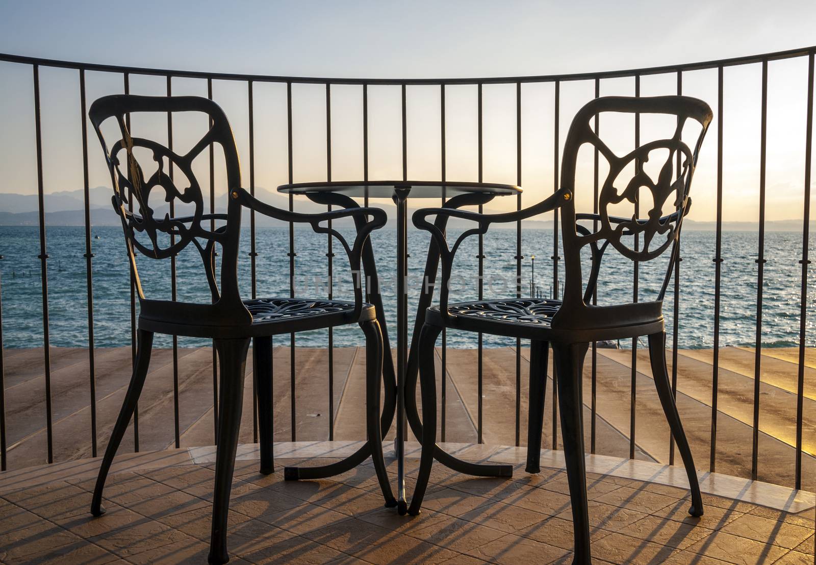 Iron chairs and table in wooden terrace lake view