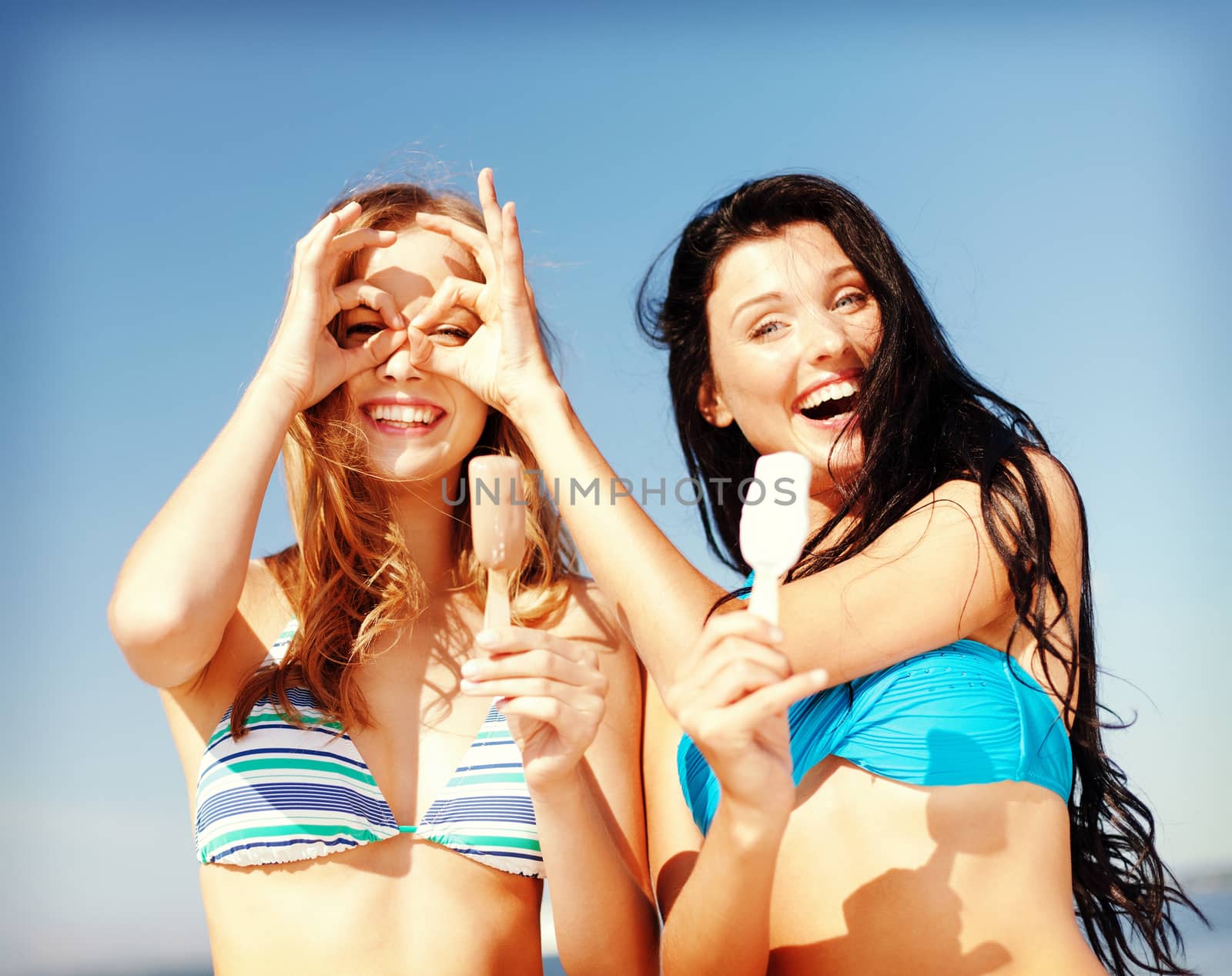 summer holidays and vacation - girls in bikinis eating ice cream on the beach