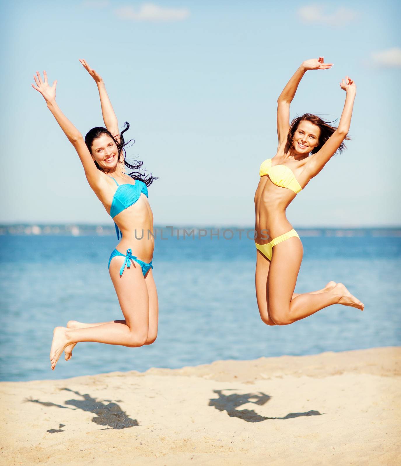 girls in bikini jumping on the beach by dolgachov