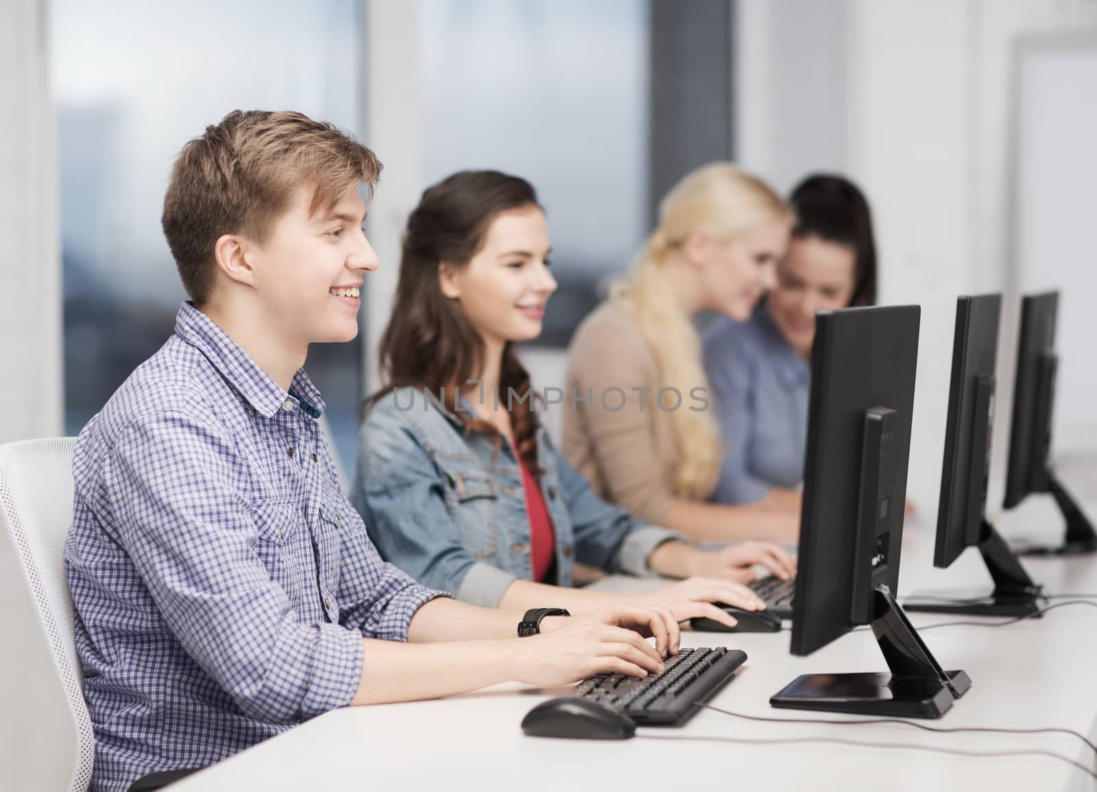students looking at computer monitor at school by dolgachov