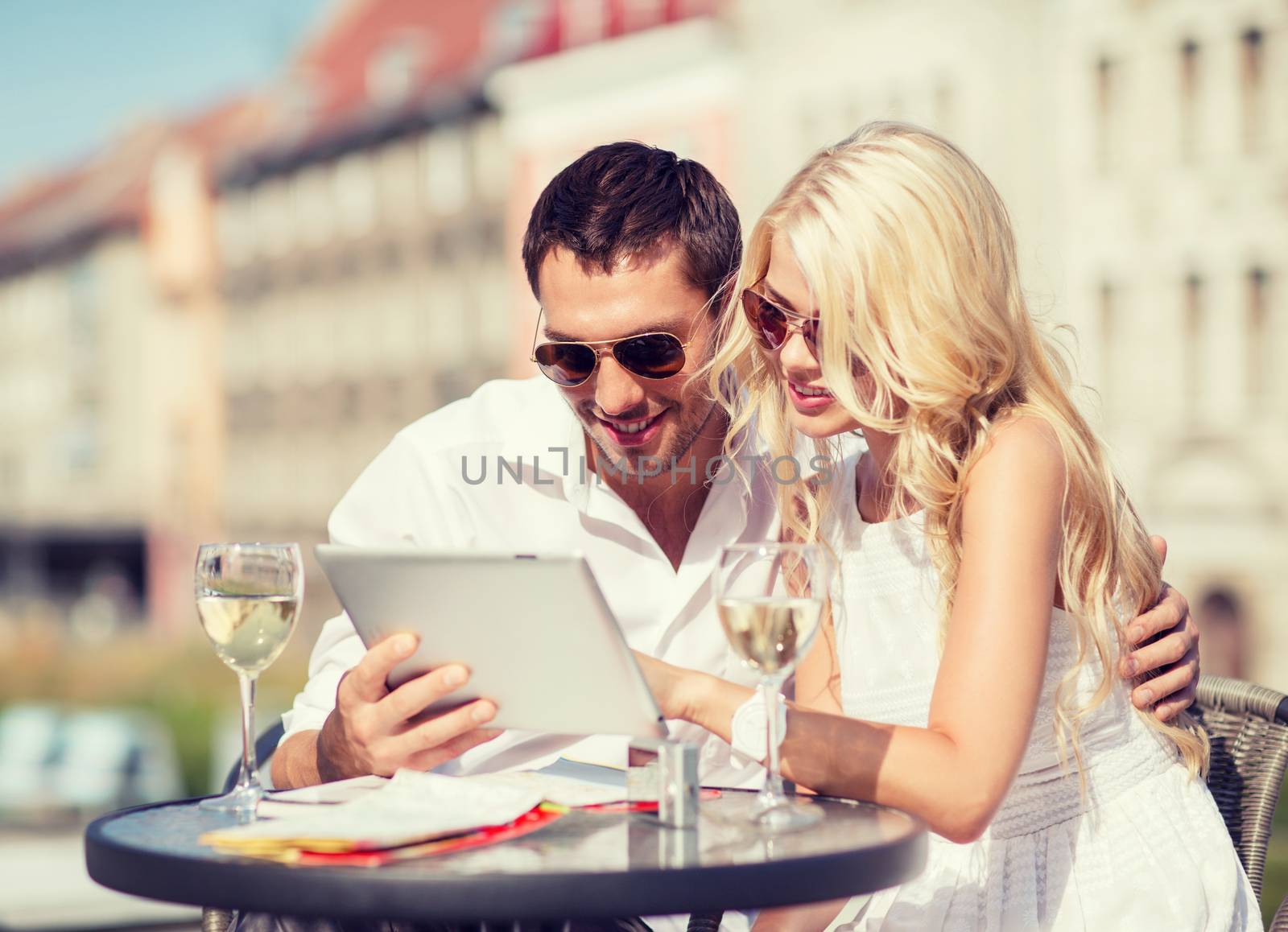 summer holidays, dating and technology concept - couple looking at tablet pc in cafe in the city