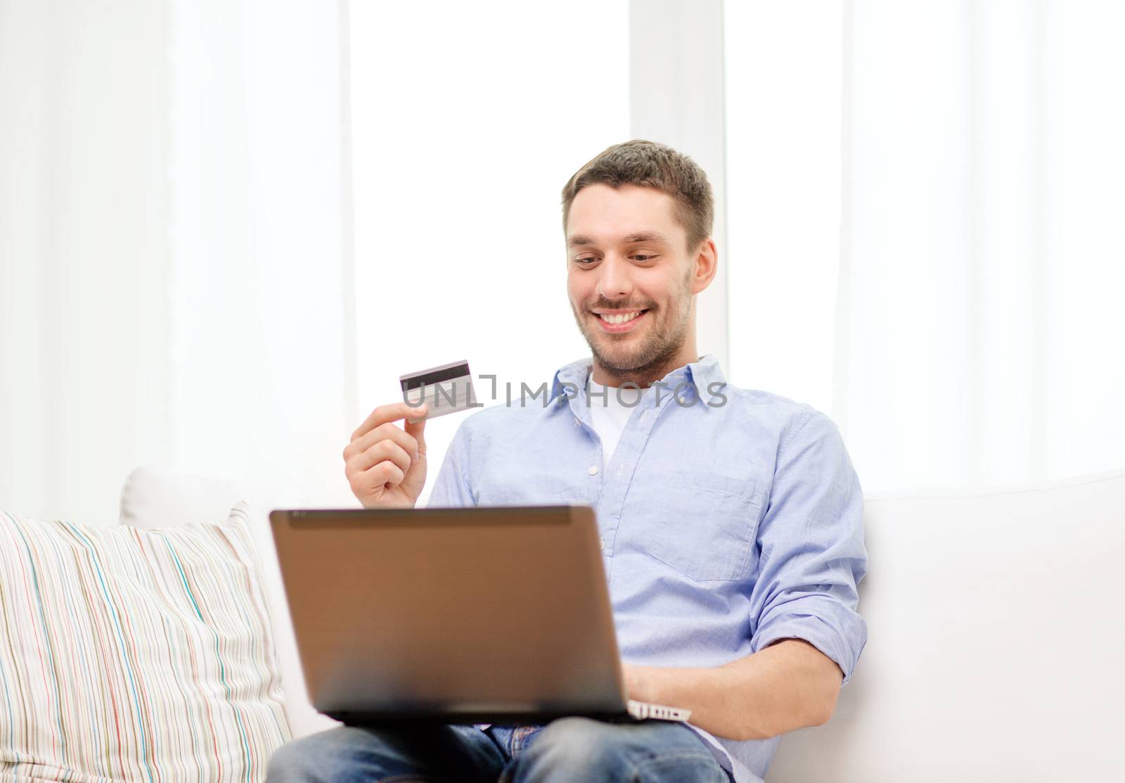 technology, home and lifestyle concept - smiling man working with laptop and credit card at home