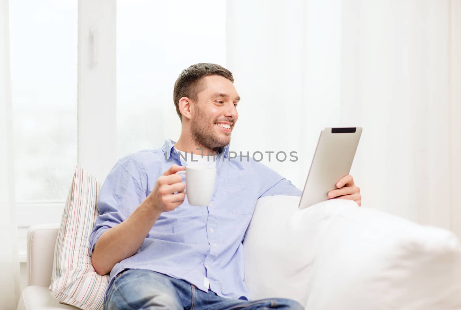 smiling man working with tablet pc at home by dolgachov