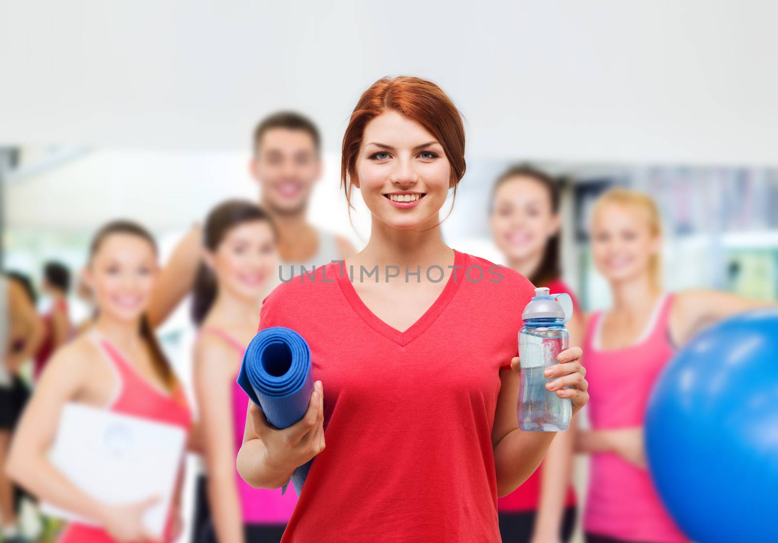 smiling girl with bottle of water after exercising by dolgachov