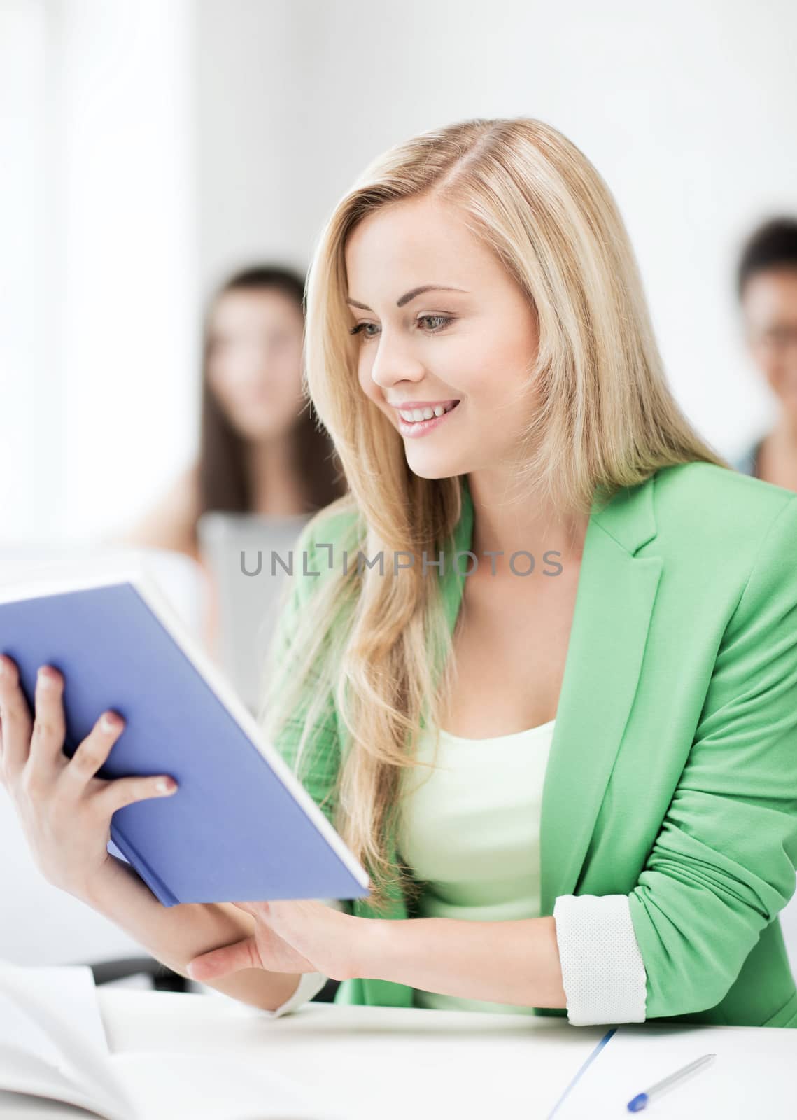 education concept - smiling young girl reading book at school