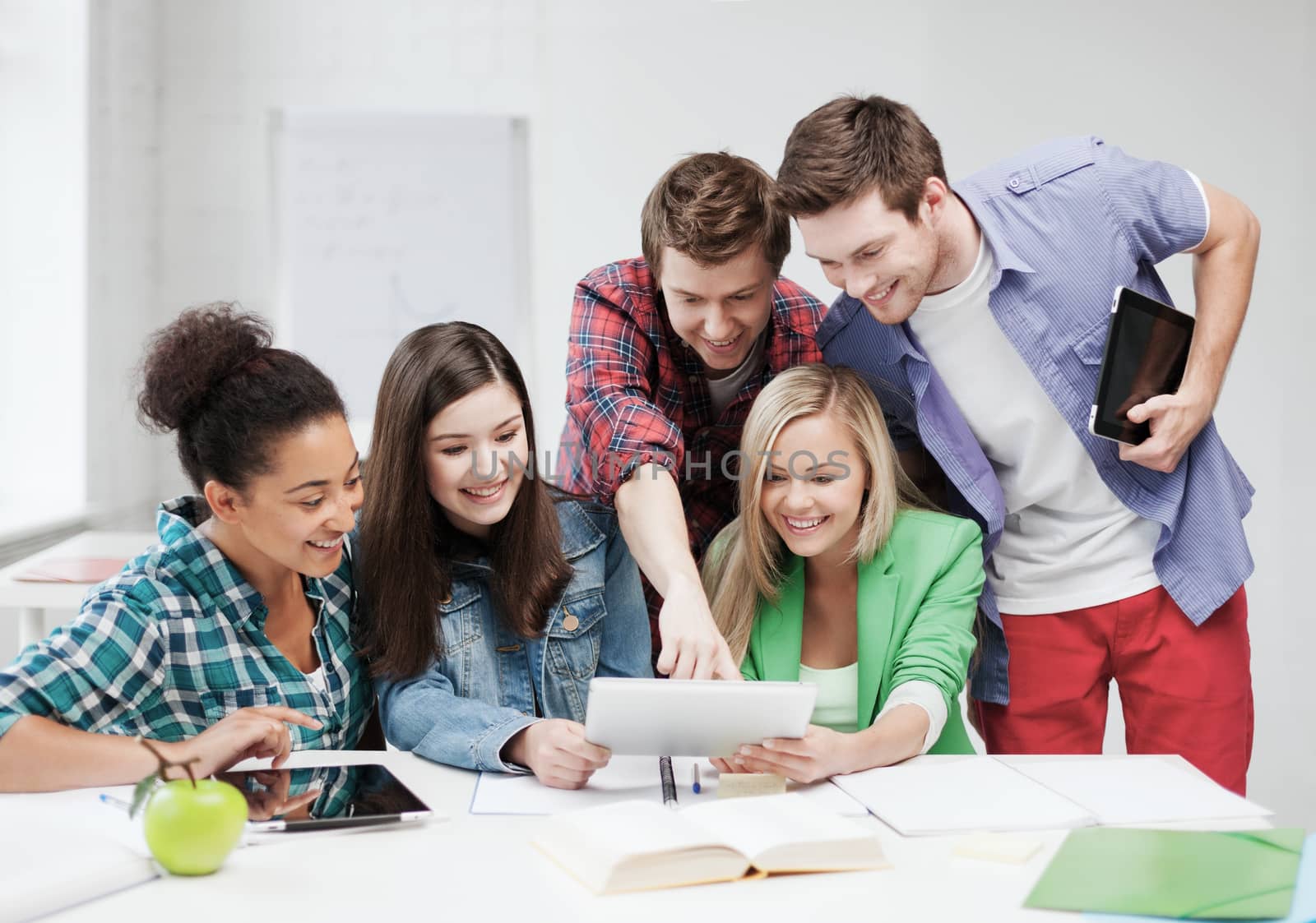 education concept - smiling students looking at tablet pc at school