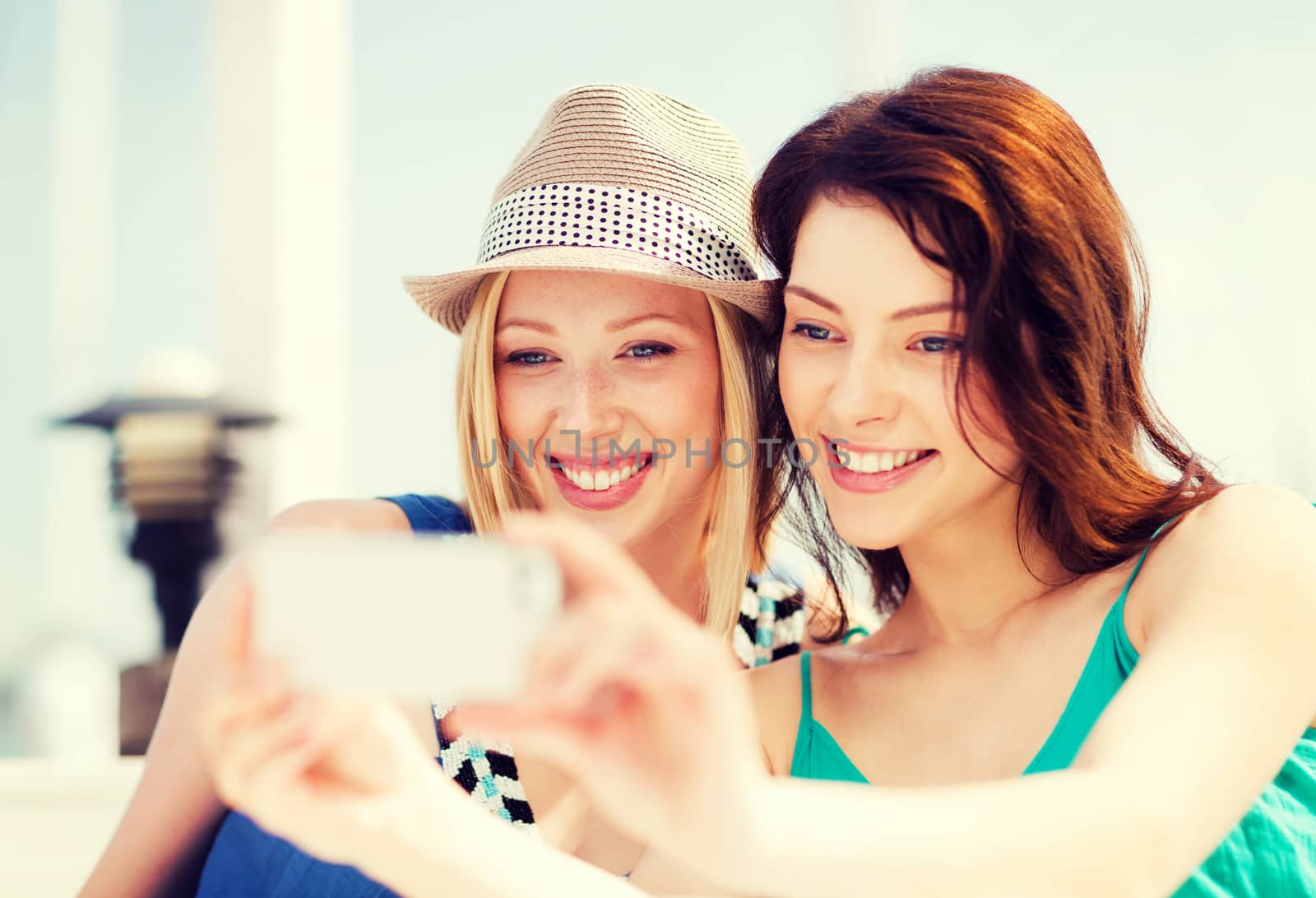summer holidays and vacation - girls taking photo in cafe on the beach