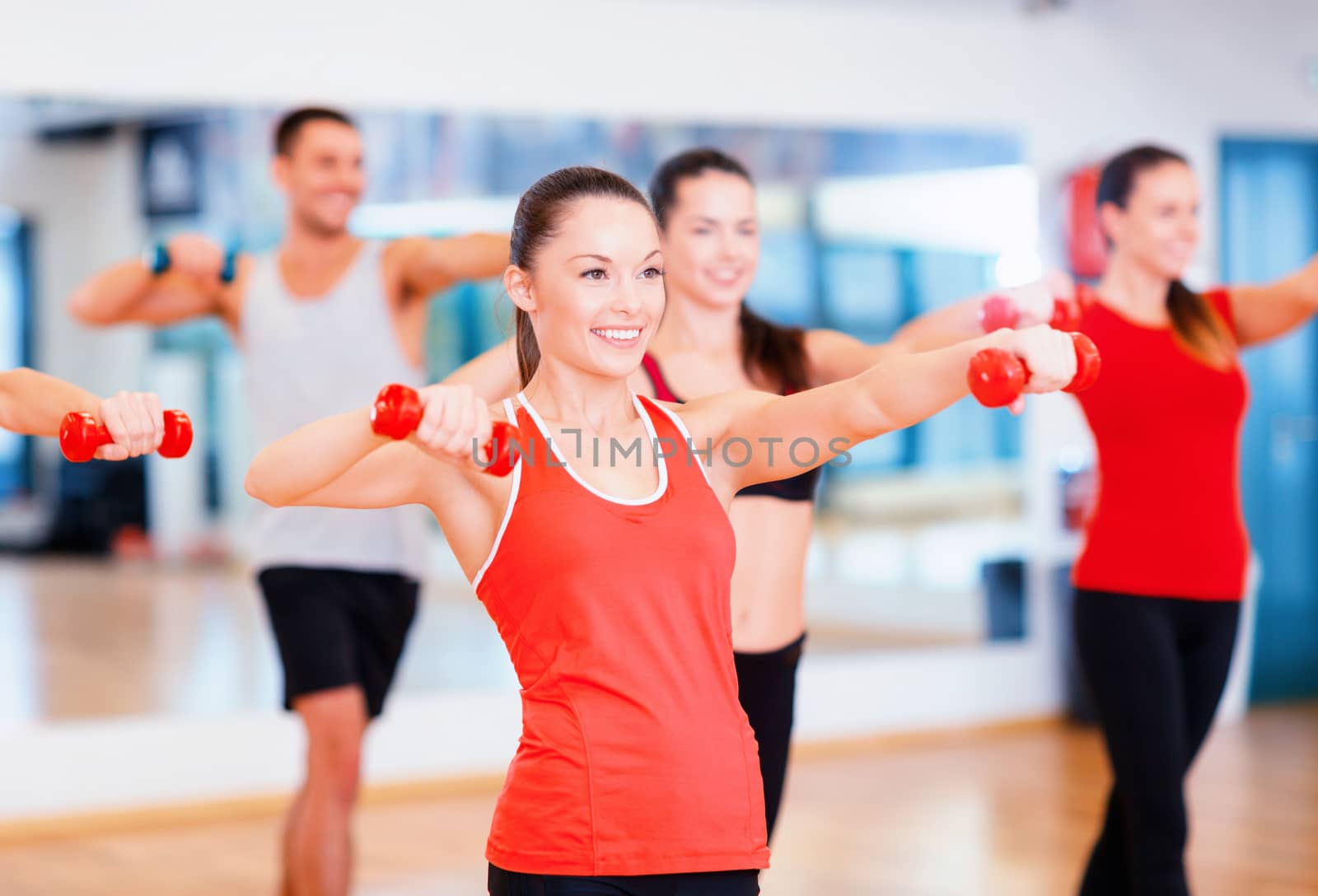 group of smiling people working out with dumbbells by dolgachov