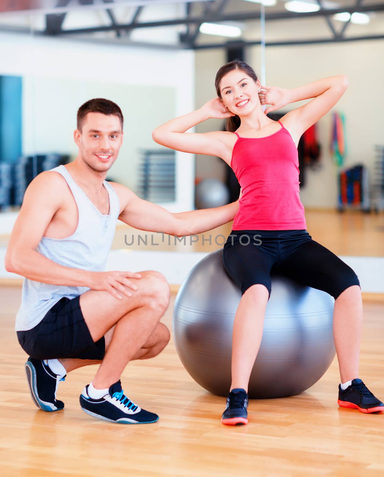 fitness, sport, training, gym and lifestyle concept - male trainer with woman doing crunches on the ball