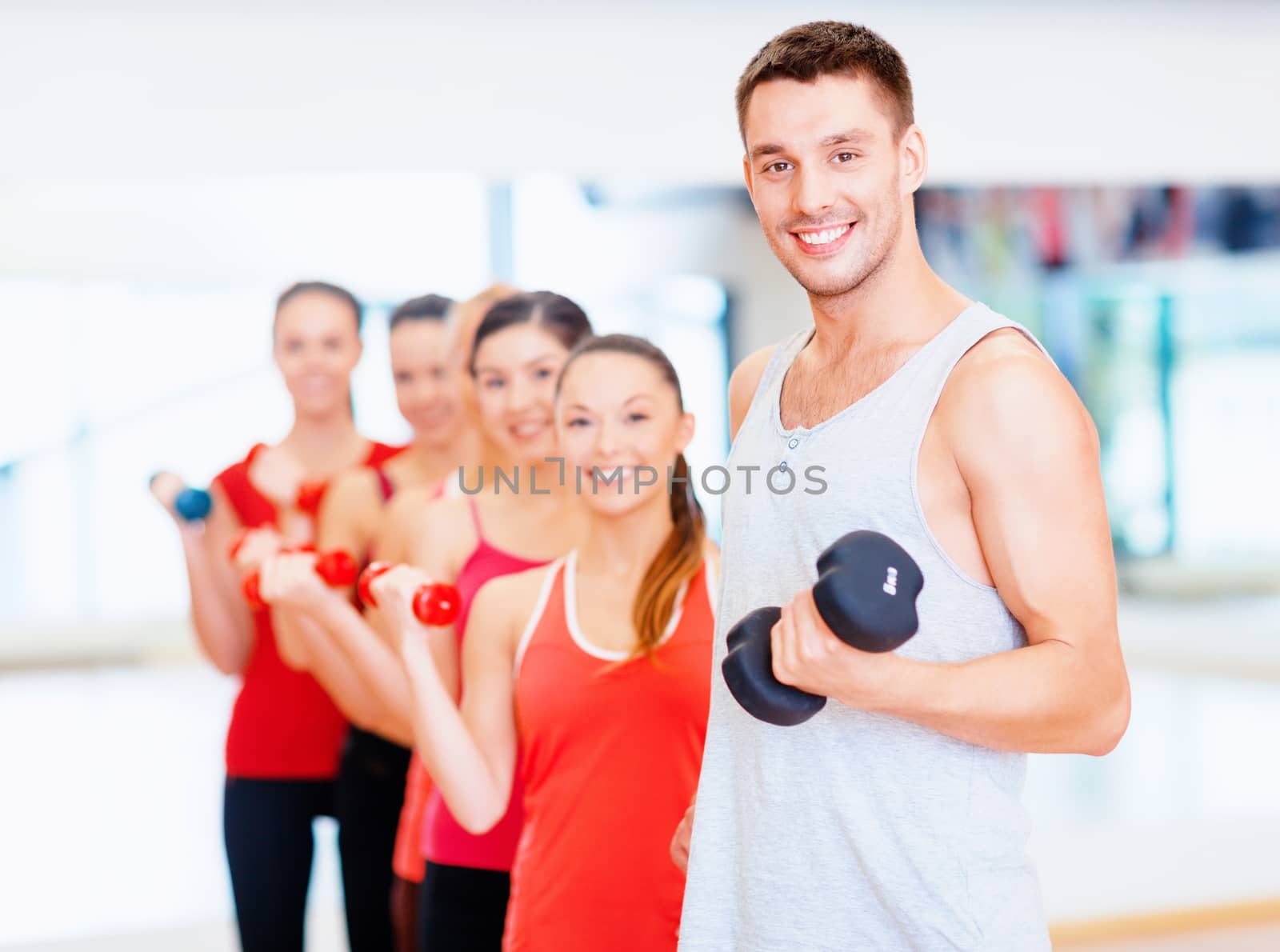 group of smiling people with dumbbells in the gym by dolgachov