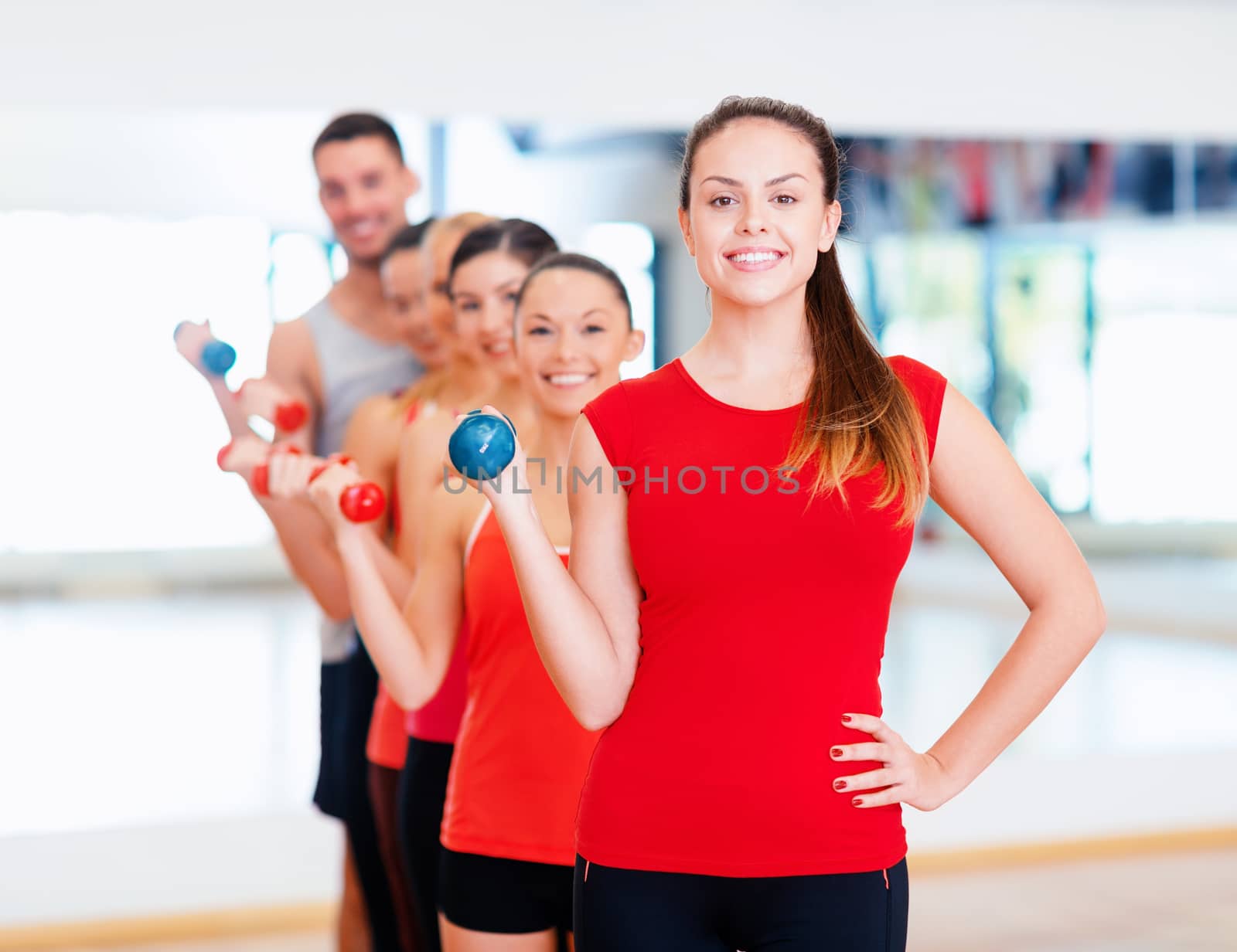 group of smiling people with dumbbells in the gym by dolgachov