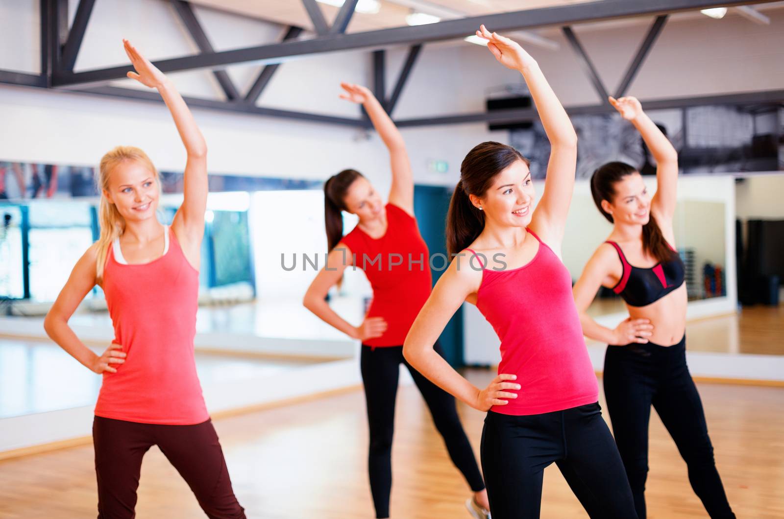 fitness, sport, training, gym and lifestyle concept - group of smiling people stretching in the gym