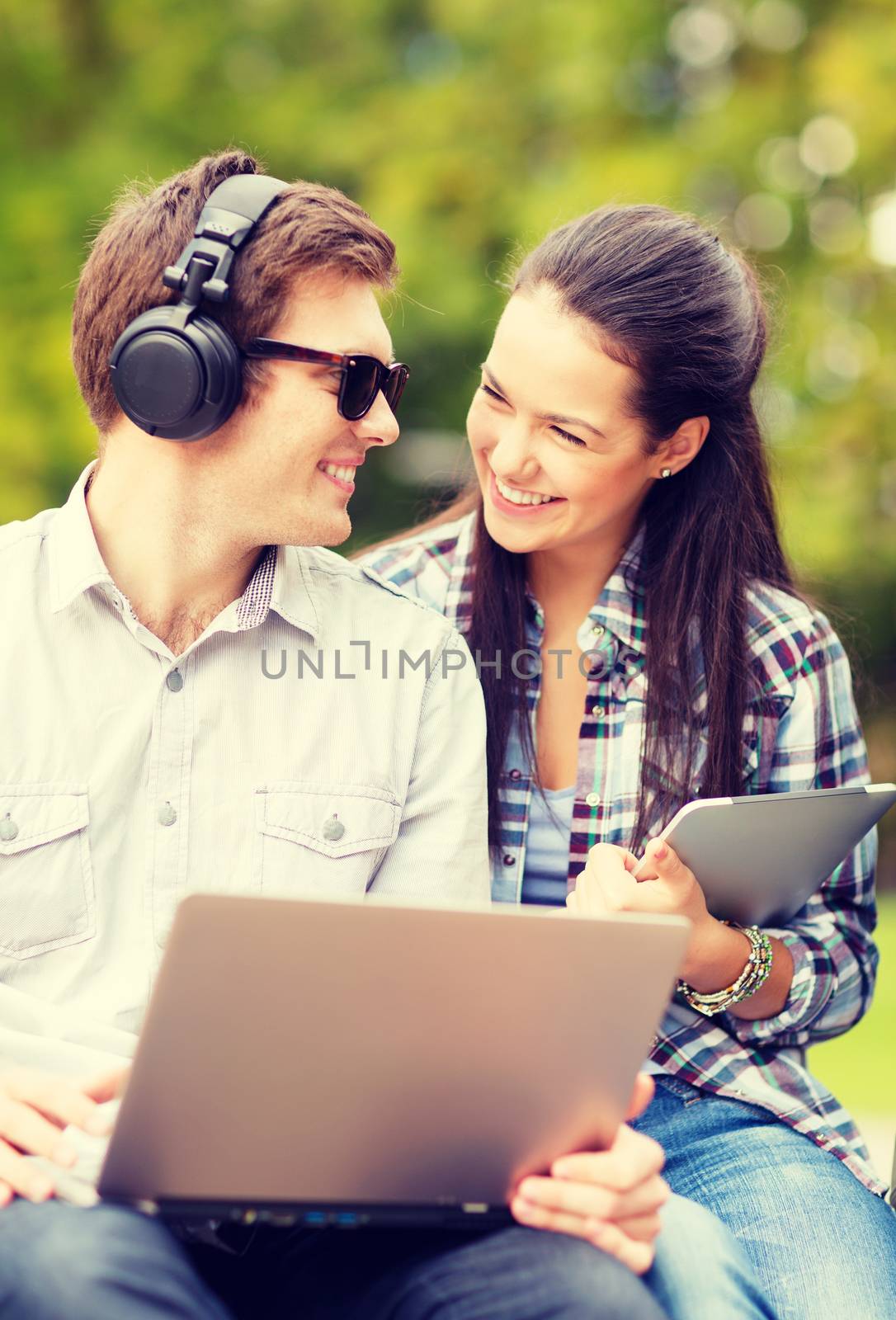 summer, internet, education, campus and teenage concept - students or teenagers with laptop and tablet computers hanging out