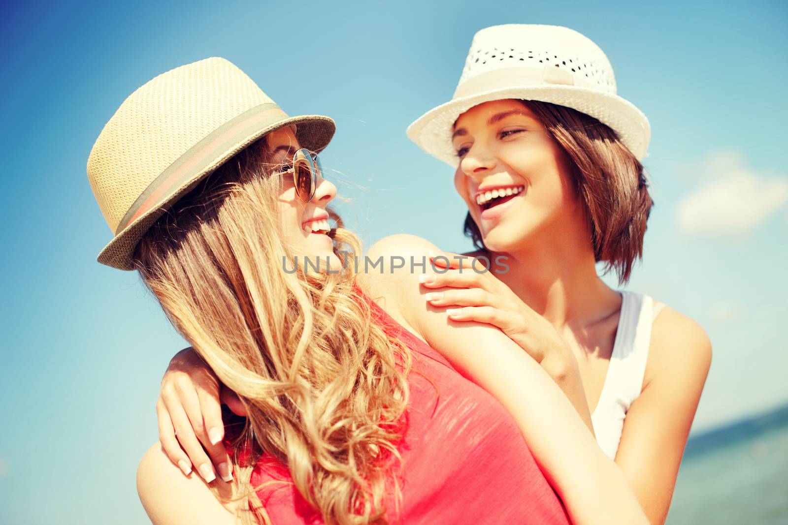 summer holidays and vacation concept - girls in hats on the beach