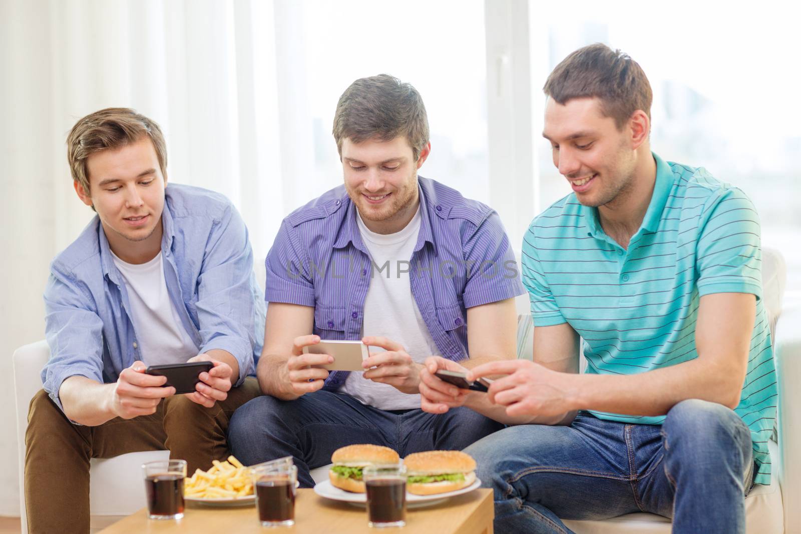 friendship, technology, food and leisure concept - smiling friends taking picture of food with smartphone camera at home