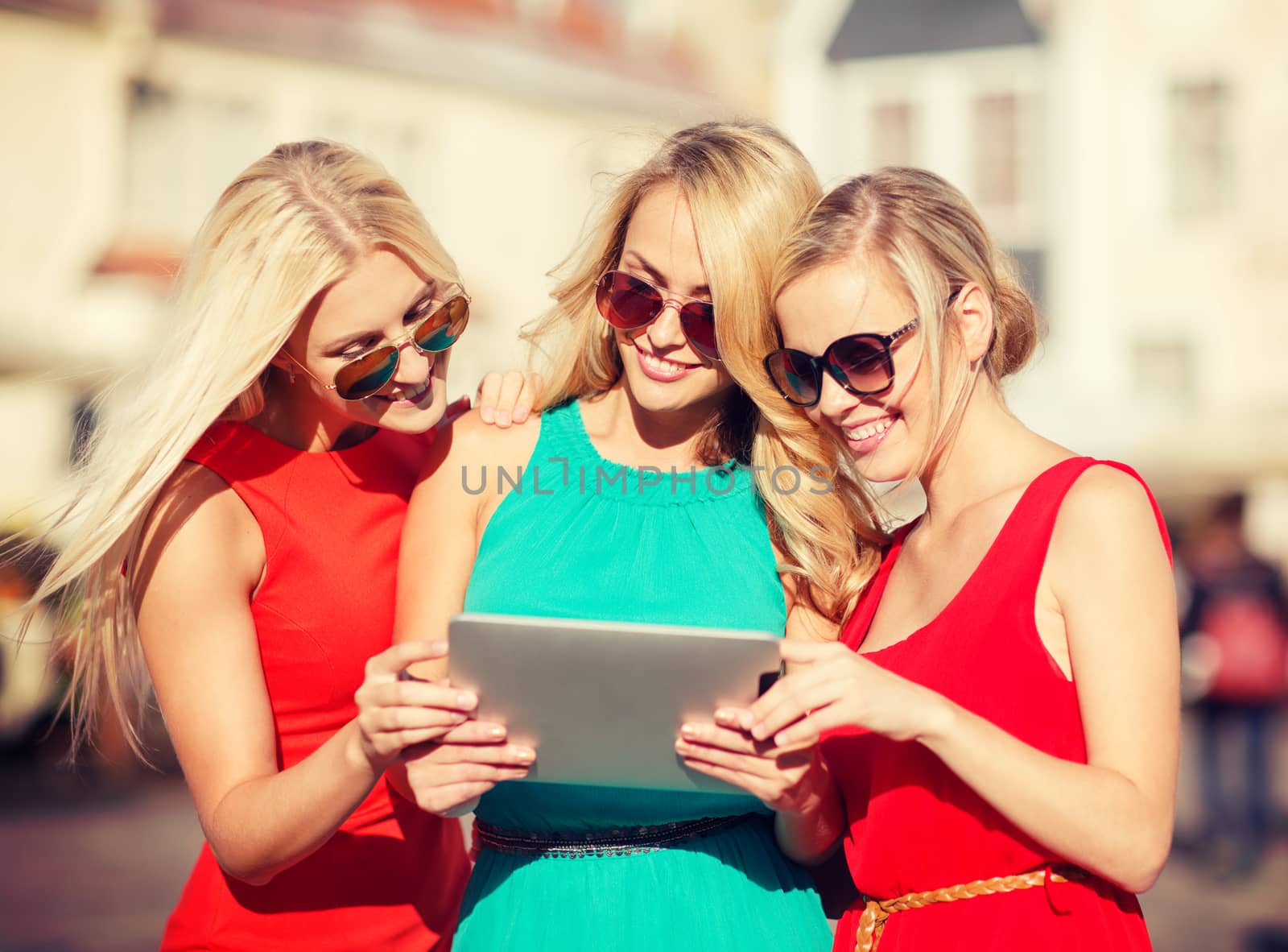 holidays and tourism concept - beautiful blonde girls toursits looking into tablet pc in the city