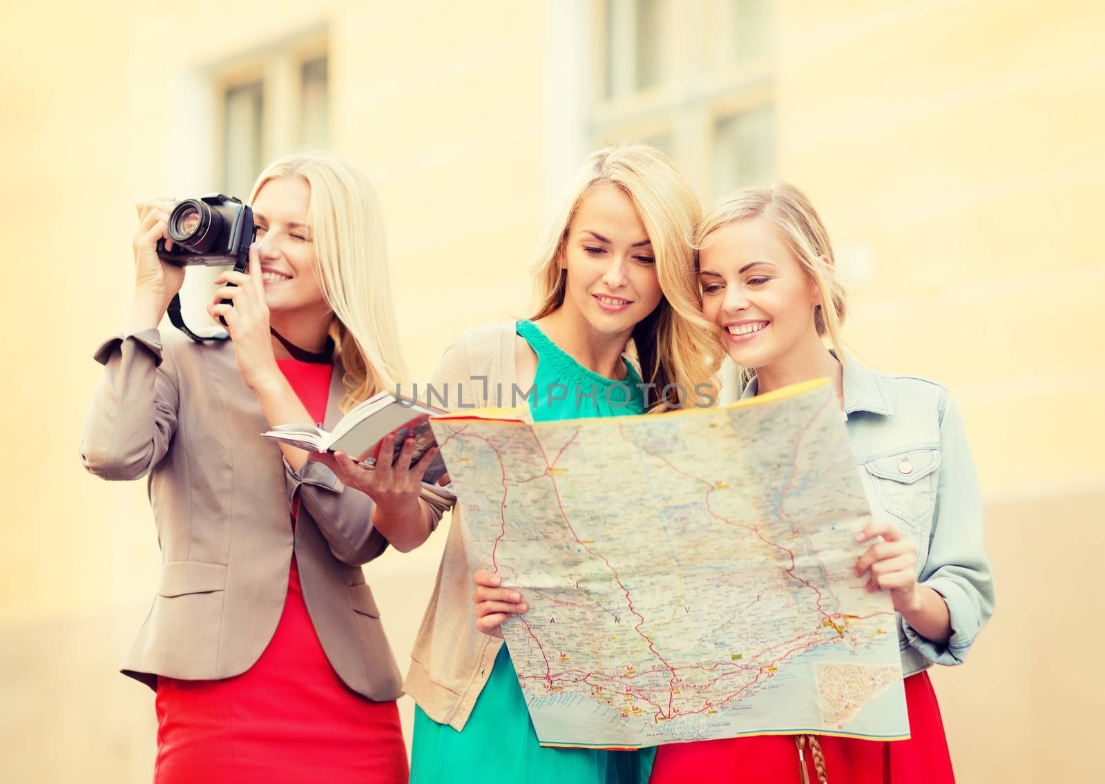holidays and tourism concept - beautiful blonde women with tourist map and photo camera in the city