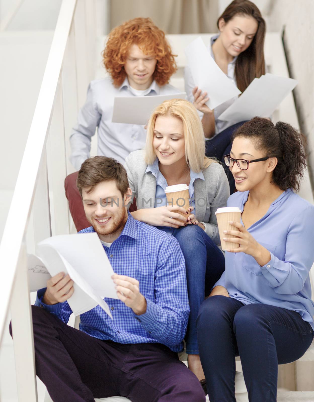 team with papers and take away coffee on staircase by dolgachov