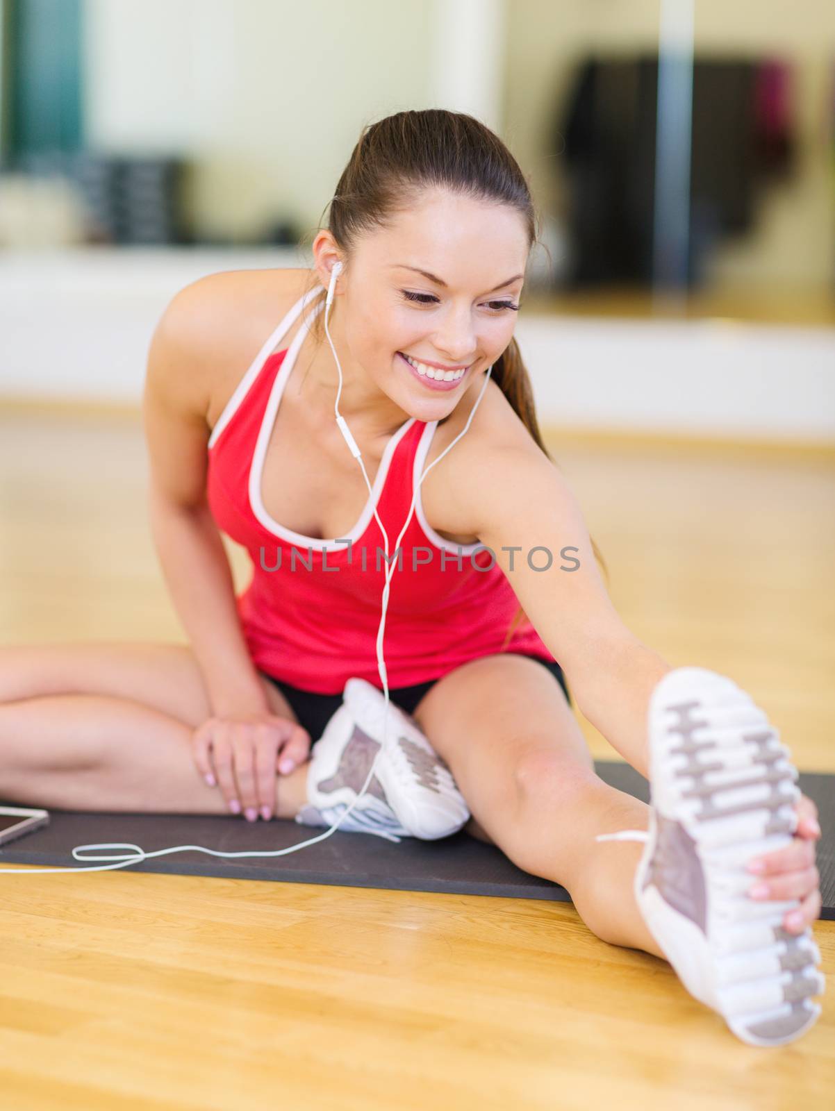 fitness, sport, training, gym, technology and lifestyle concept - smiling teenage girl with smartphone and earphones in gym