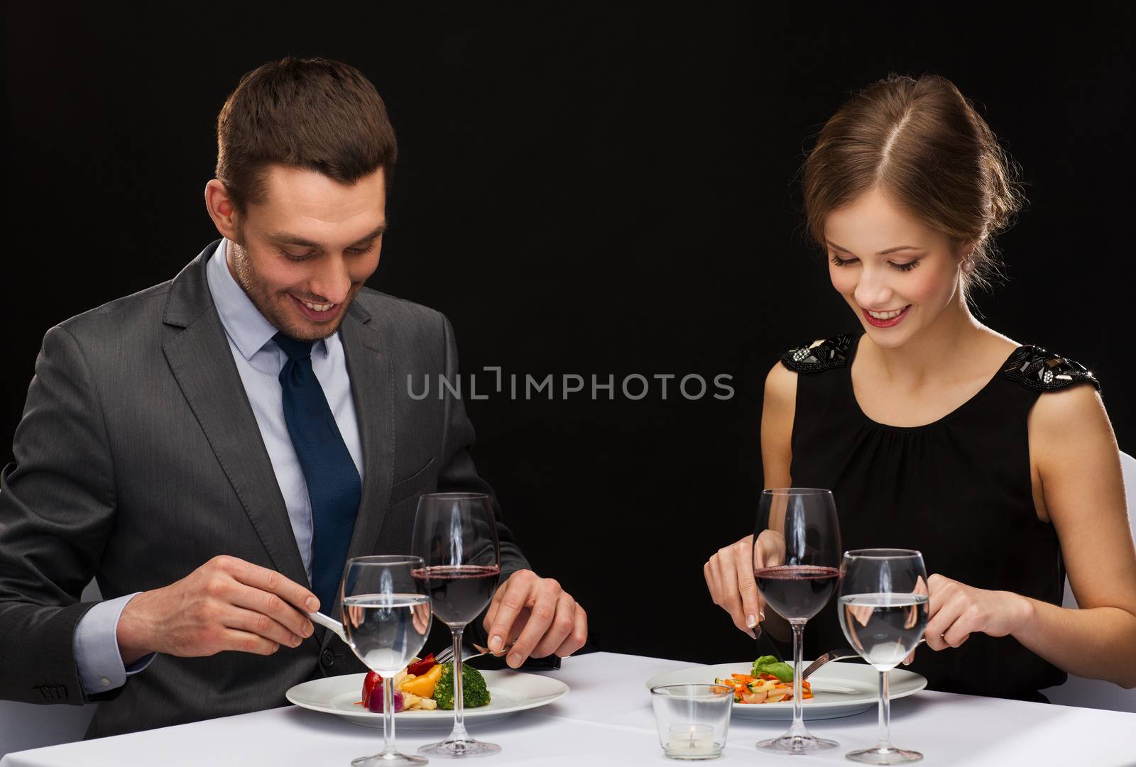 restaurant, couple and holiday concept - smiling couple eating main course with red wine at restaurant