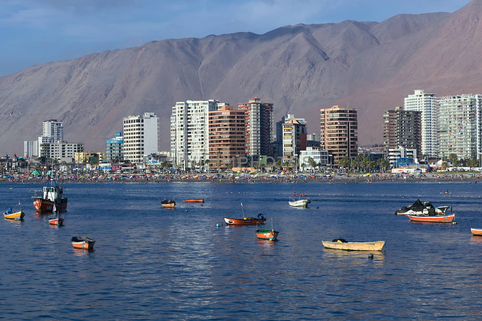 IQUIQUE, CHILE - JANUARY 23, 2015: View from the peninsula at the end of Cavancha beach over the fishing boats anchoring in the bay, Cavancha beach and the modern tall buildings along Arturo Prat Chacon Avenue on January 23, 2015 in Iquique, Chile. Iquique is a popular beach town and free port city in Northern Chile. 