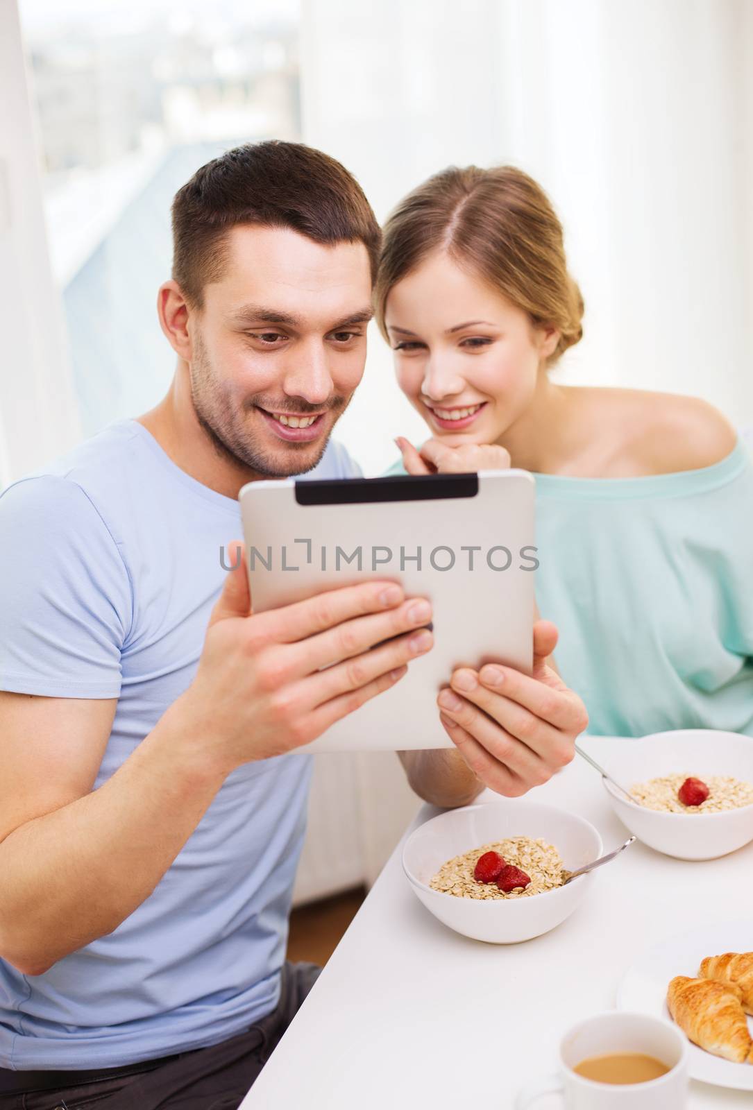 food, home, couple and technology concept - smiling couple with tablet pc reading news or taking picture and having breakfast at home