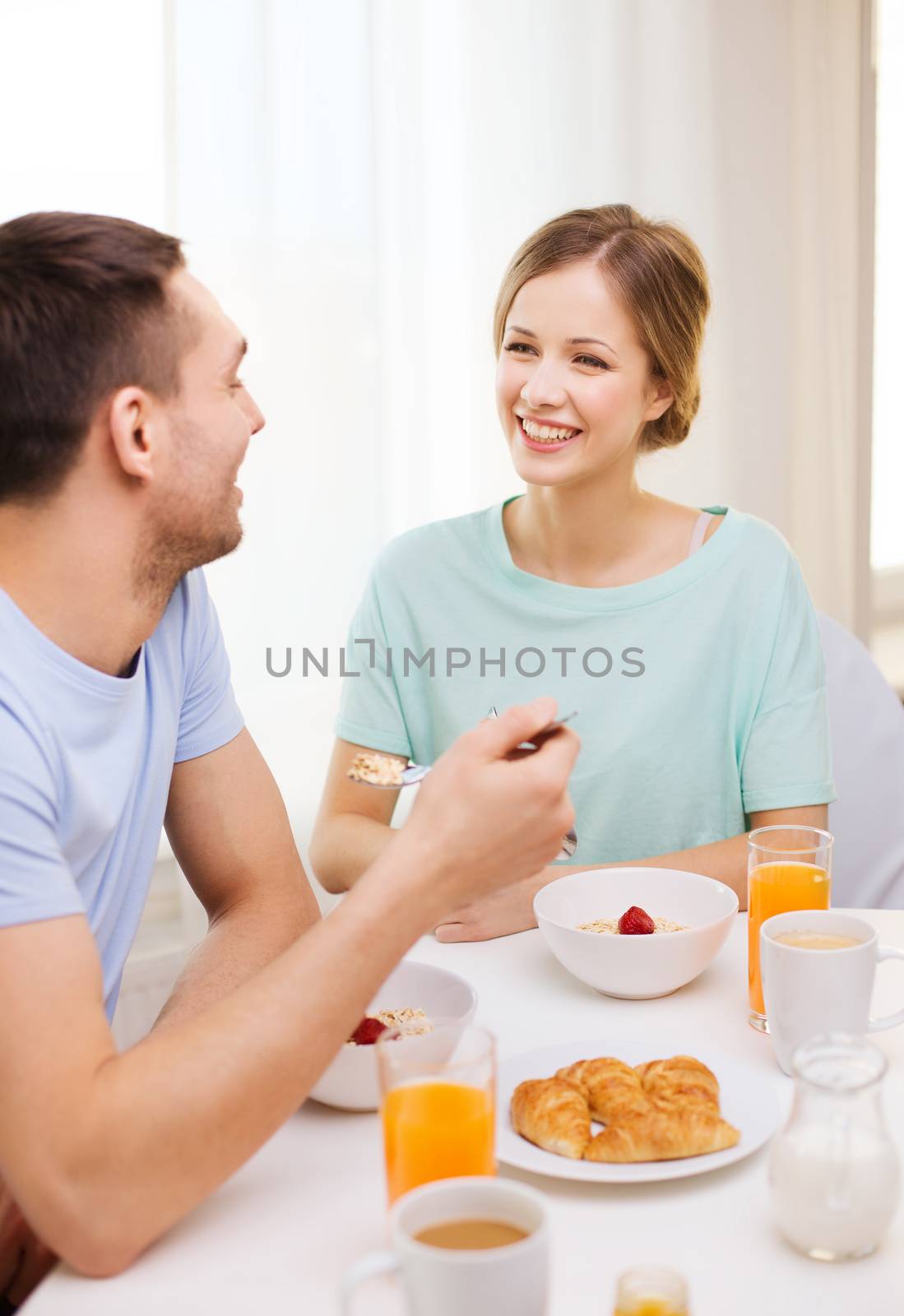 smiling couple having breakfast at home by dolgachov