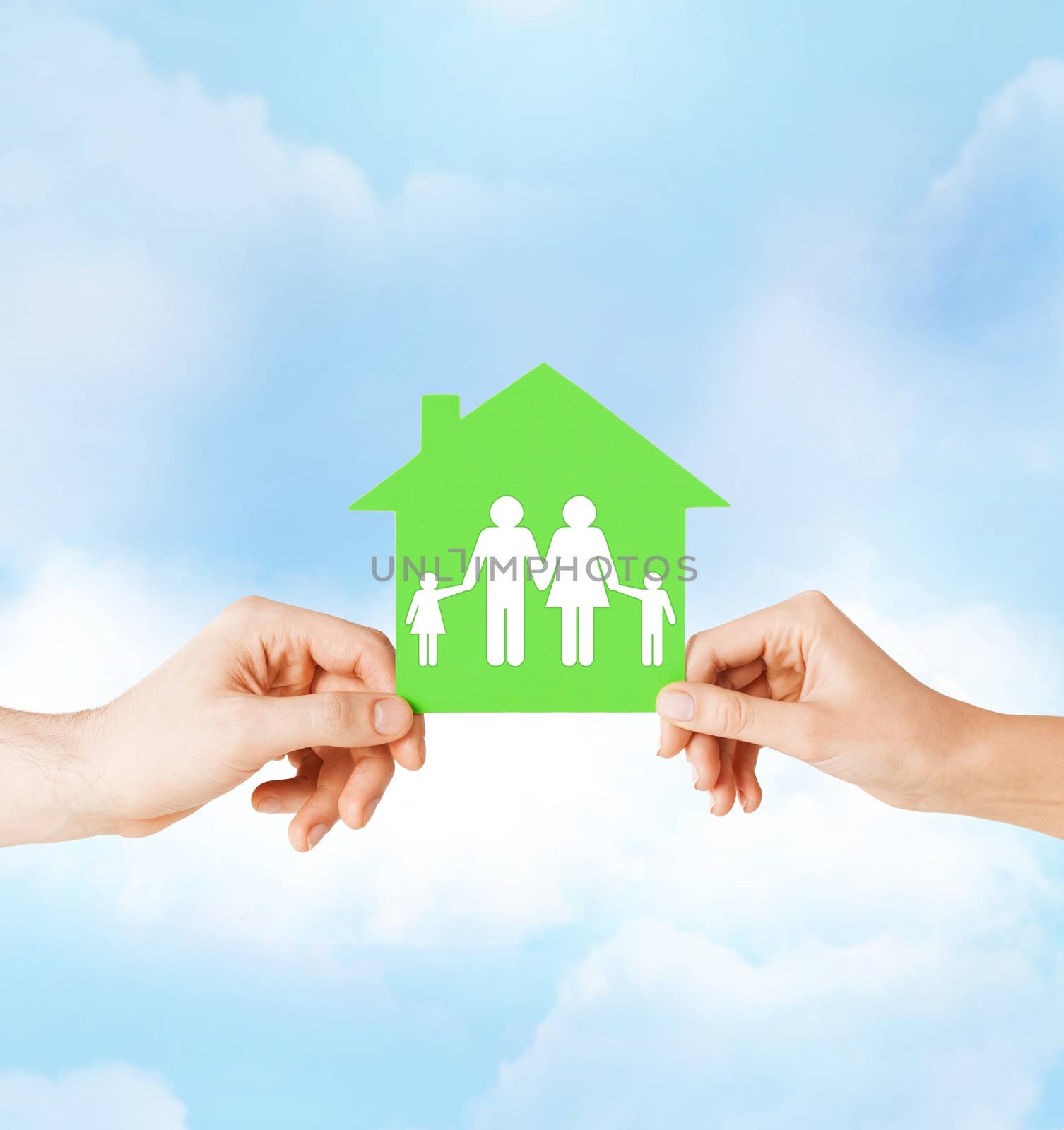 real estate and family home concept - isolated picture of male and female hands holding green paper house with family