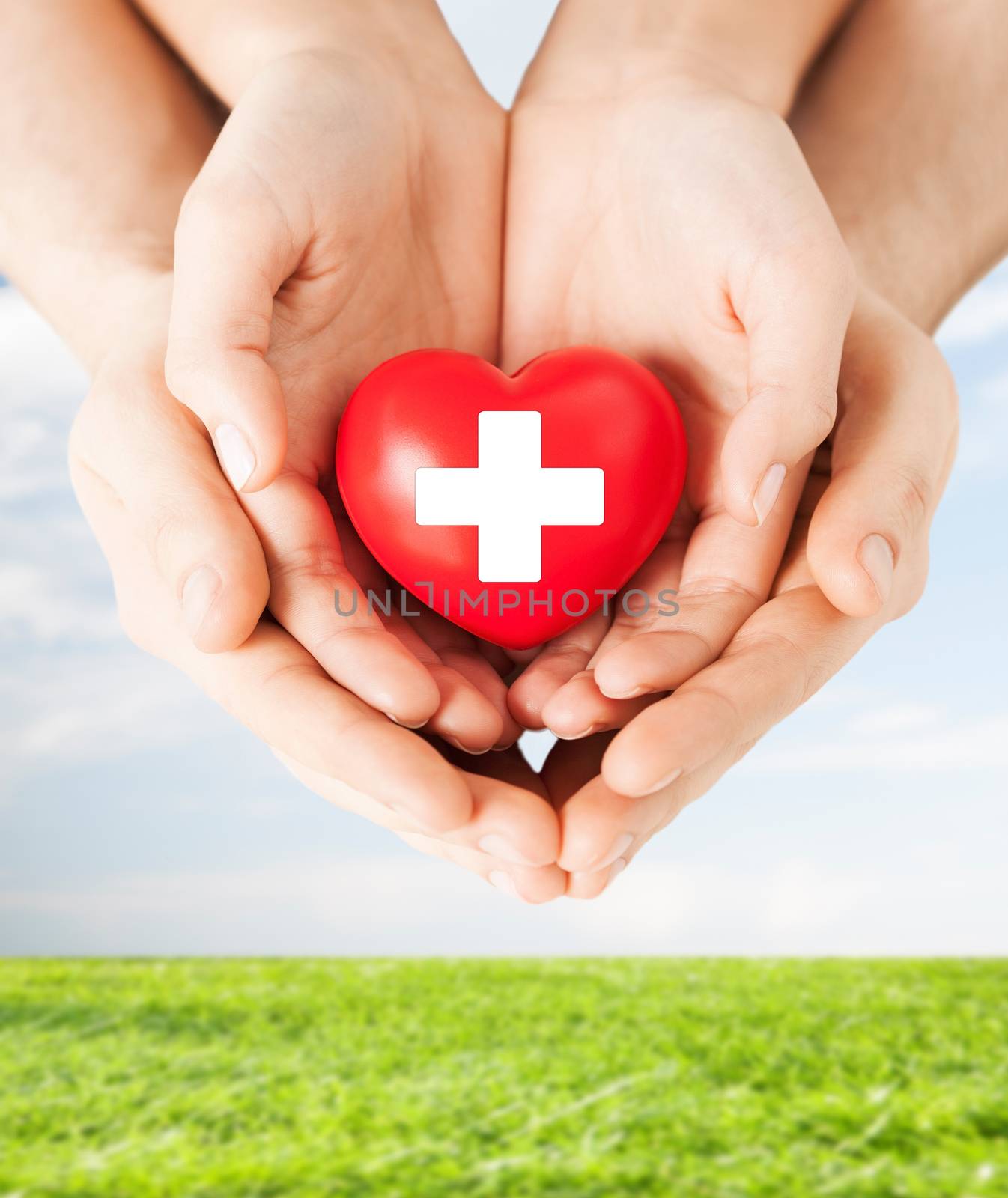 family health, charity and medicine concept - male and female hands holding red heart with cross sign