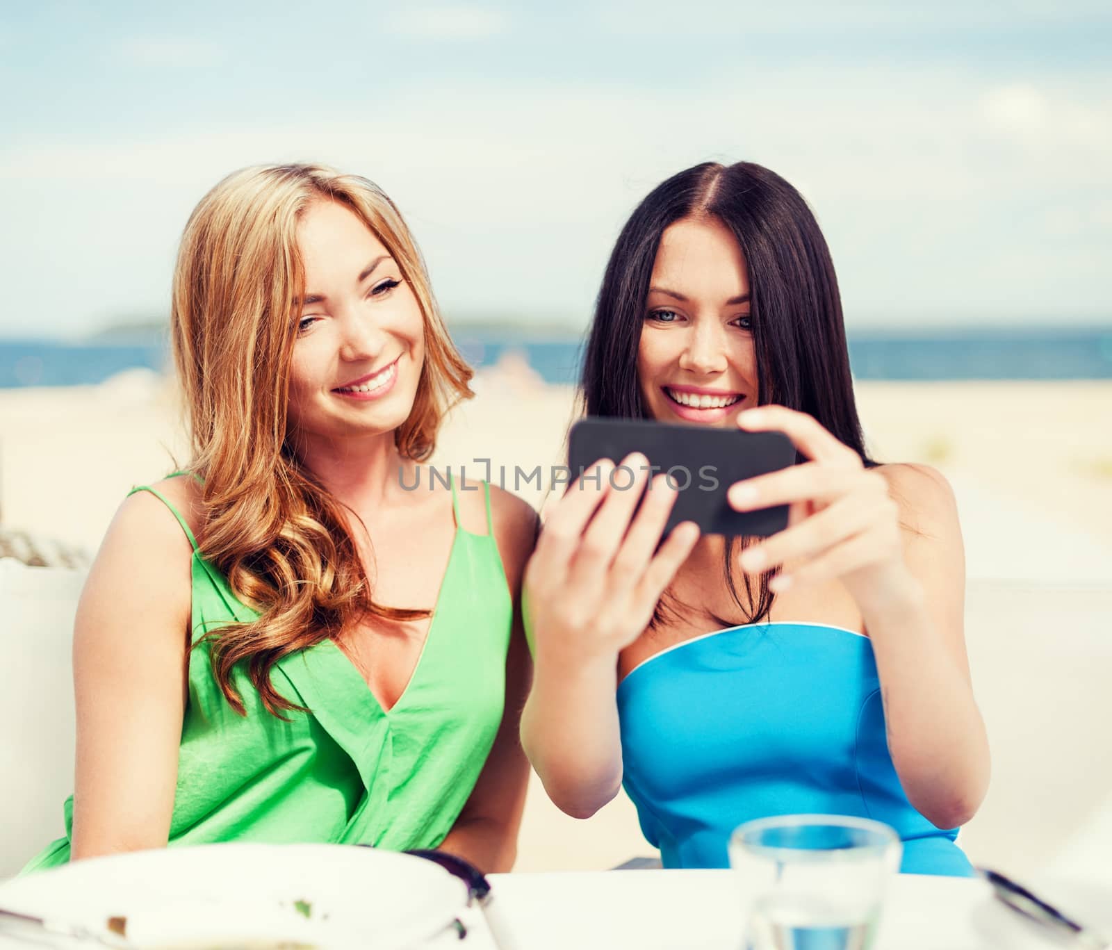 summer holidays, vacation and technology - girls taking photo with smartphone in cafe on the beach