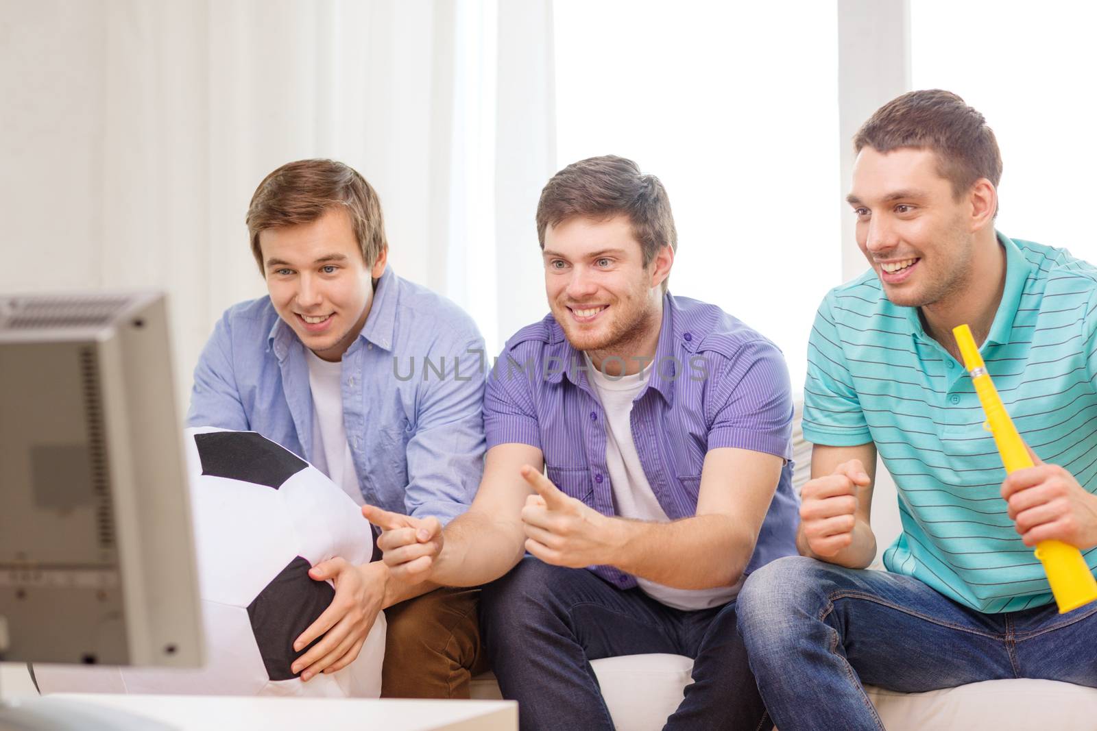 friendship, sports and entertainment concept - happy male friends with football and vuvuzela supporting football team at home