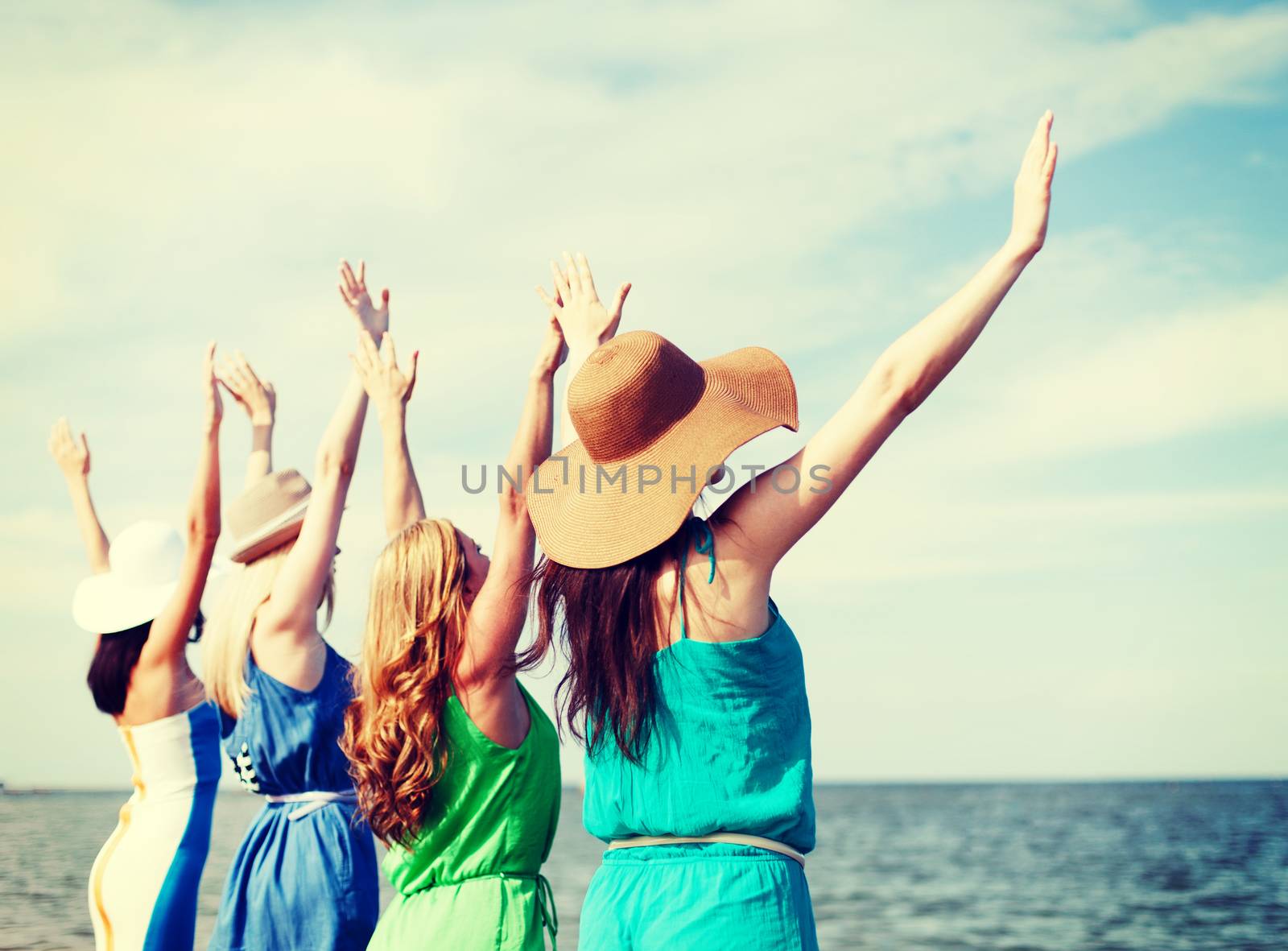 summer holidays and vacation - girls with hands up on the beach