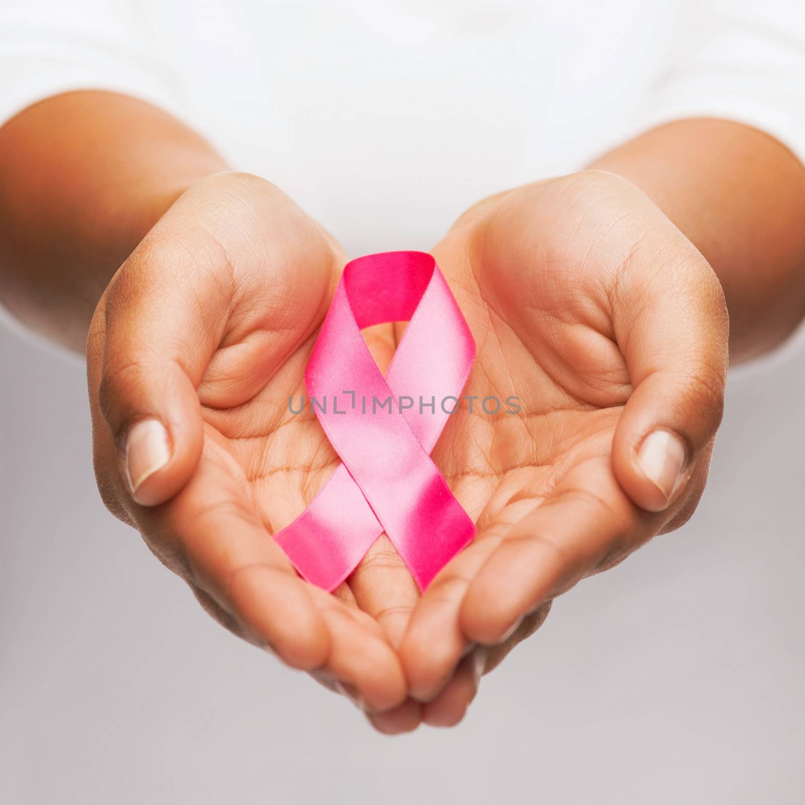 hands holding pink breast cancer awareness ribbon by dolgachov