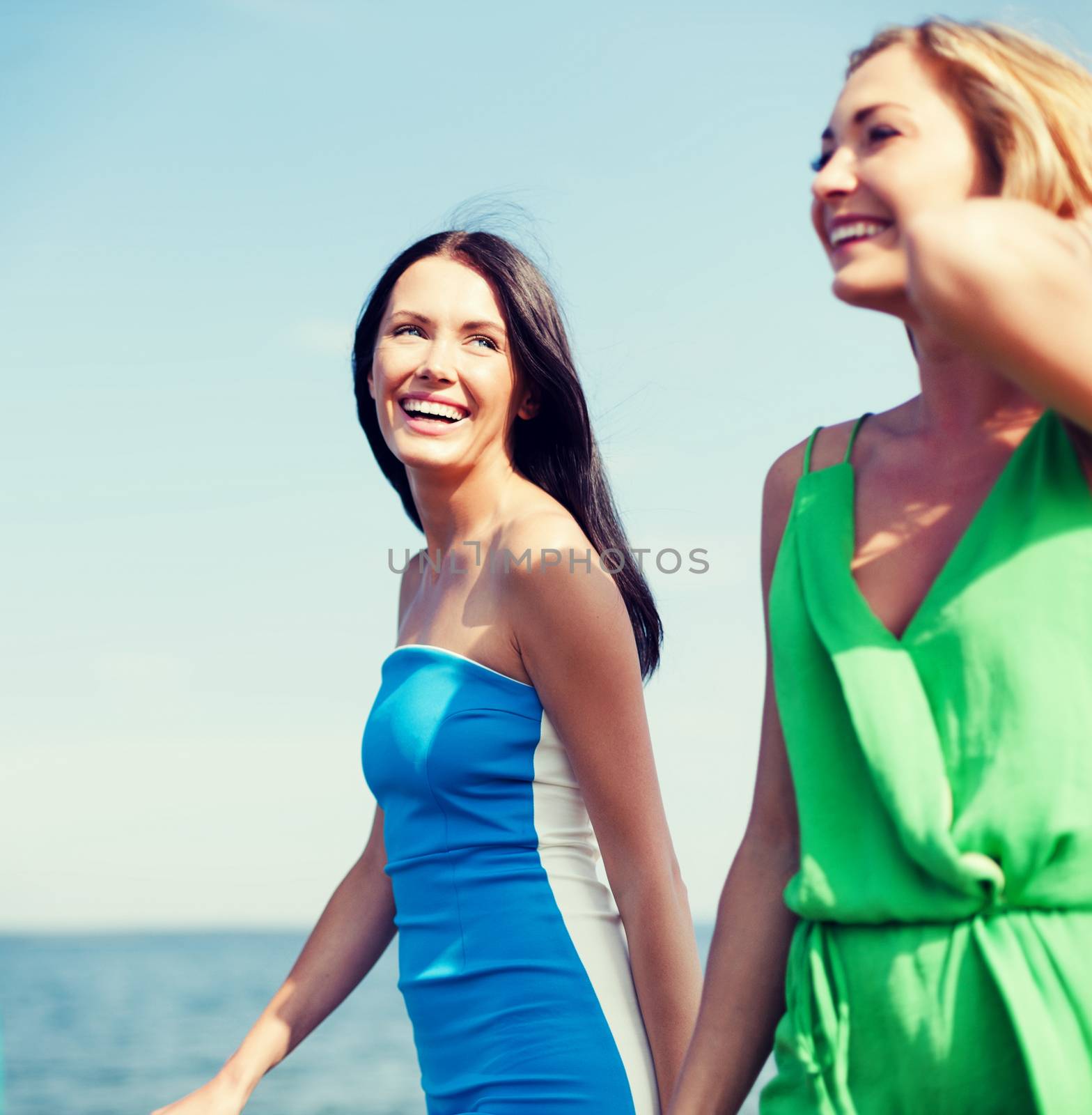 summer holidays and vacation concept - girls walking on the beach