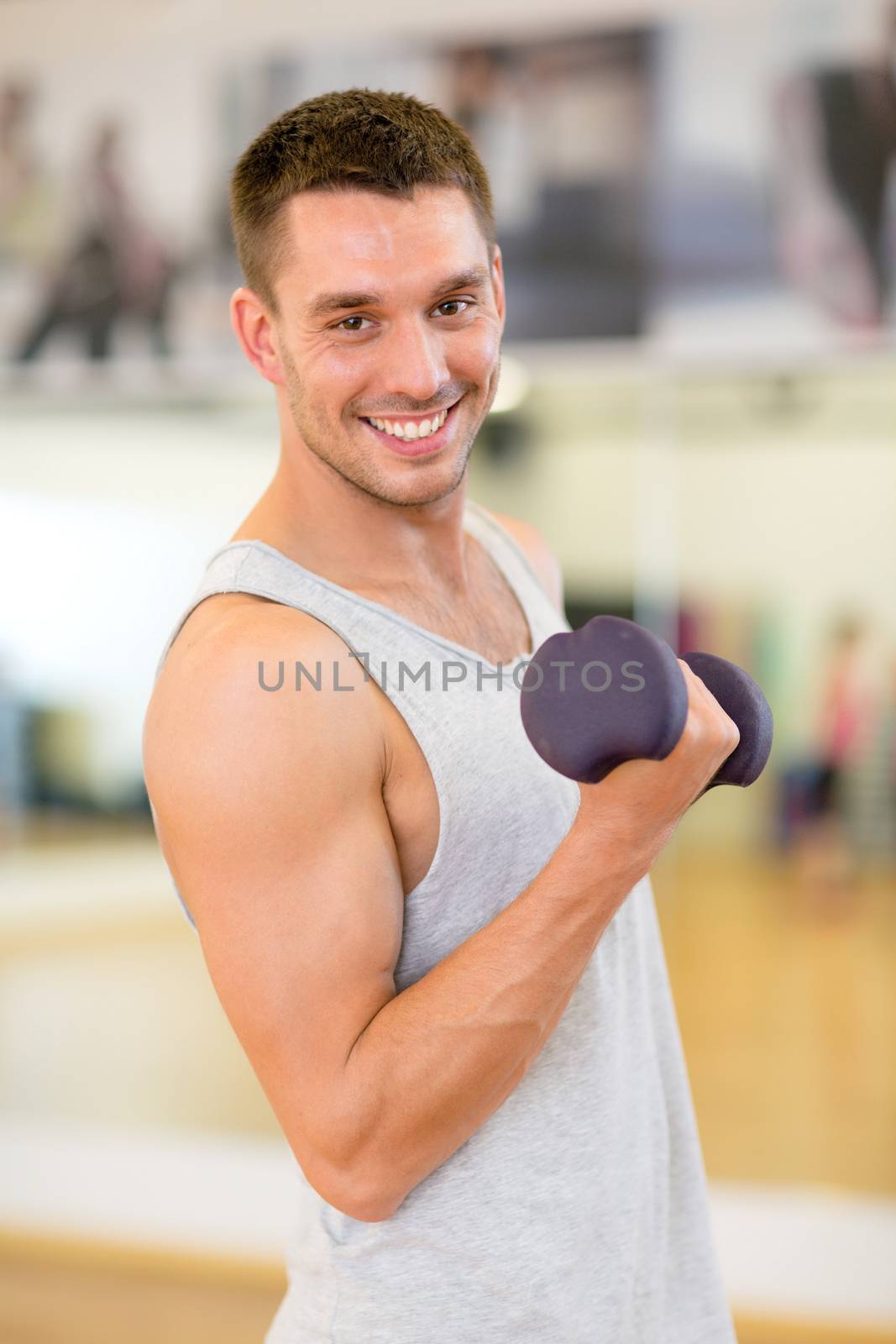 smiling man with dumbbell in gym by dolgachov