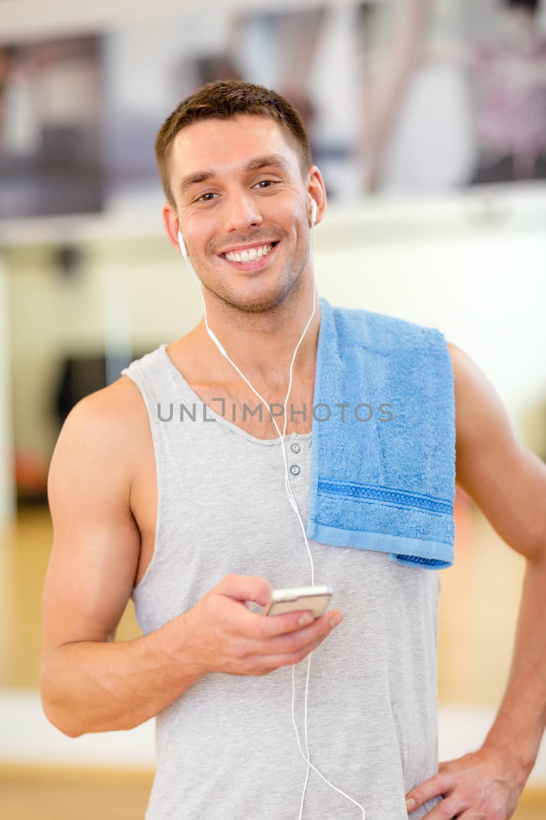 young man with smartphone and towel in gym by dolgachov