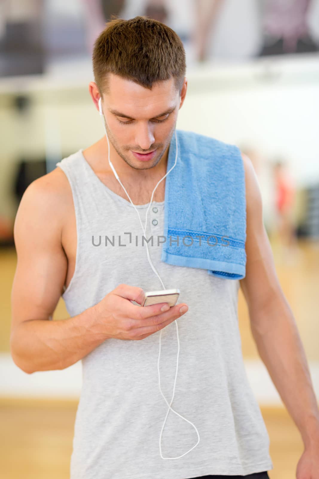 fitness, sport, training, gym, technology and lifestyle concept - young man with smartphone and towel in gym