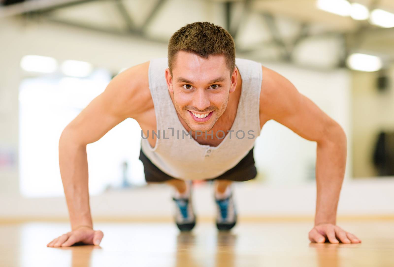 smiling man doing push-ups in the gym by dolgachov