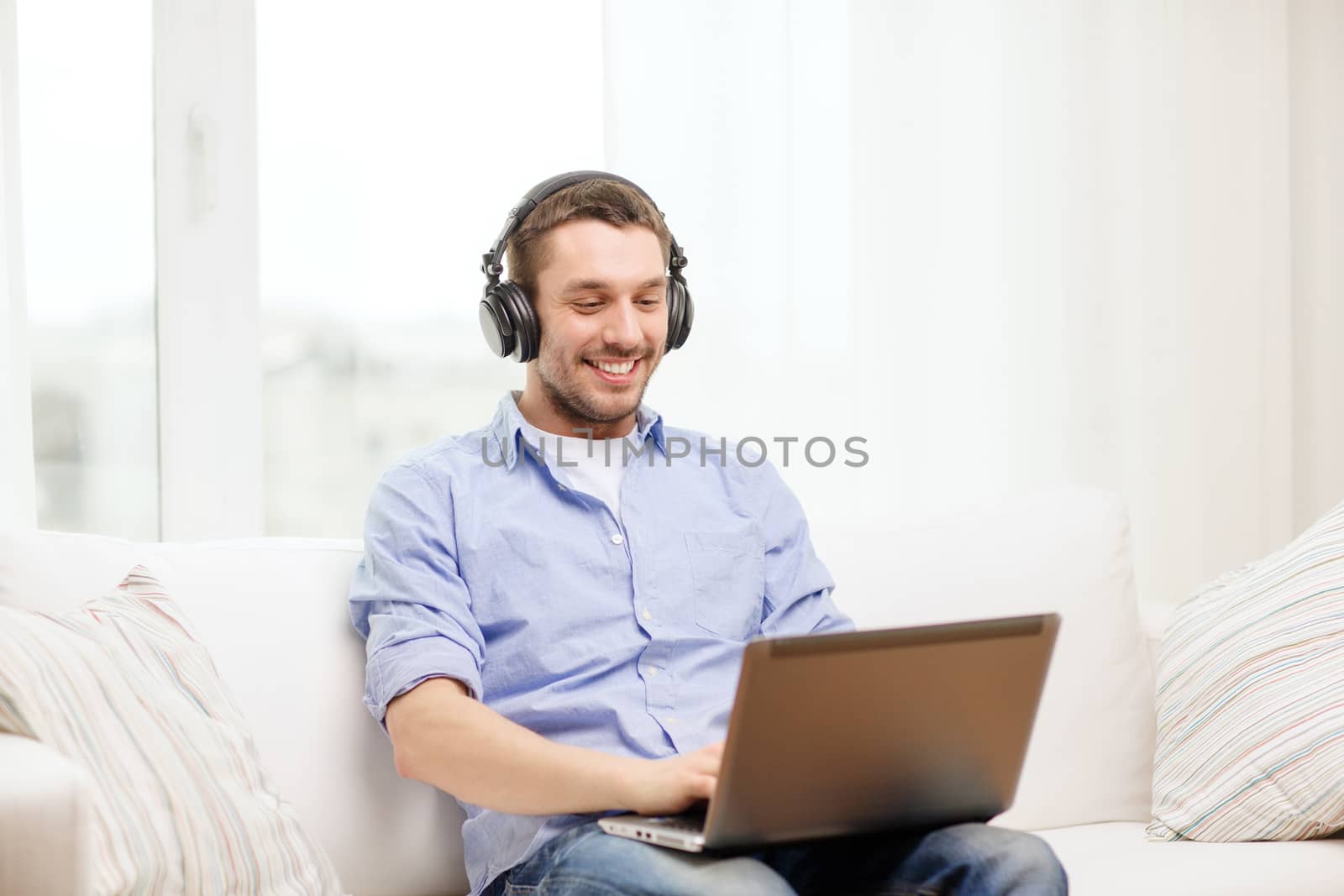 technology, home, music and lifestyle concept - smiling man with laptop and headphones at home